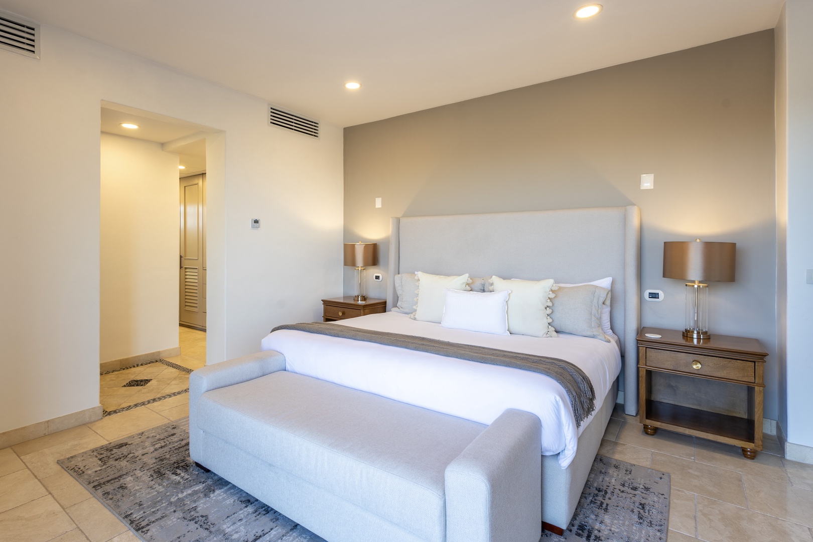 Slip into crisp white linens and sink into your plush upholstered bed—this serene bedroom invites restful nights with soft lighting and elegant touches at every turn.