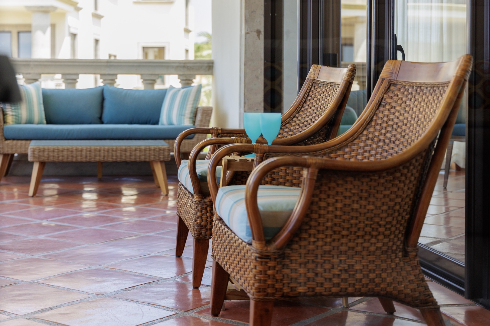 Sink into these inviting woven chairs on your private balcony, where turquoise cushions echo coastal comfort and your own outdoor retreat awaits just beyond sliding glass doors.