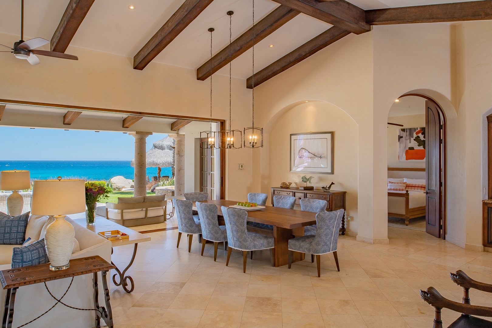 Gather with family in this elegant dining space where exposed beams frame turquoise ocean views through soaring windows.