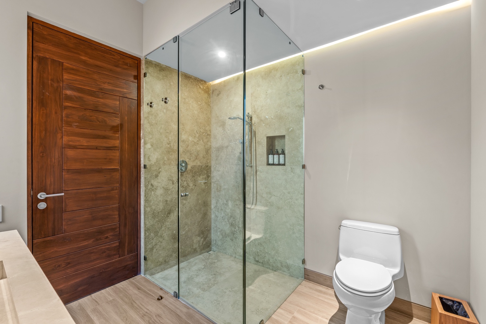 Step into your private spa-like bathroom with a spacious glass-enclosed shower, sleek modern fixtures, and warm ambient lighting designed for ultimate relaxation.