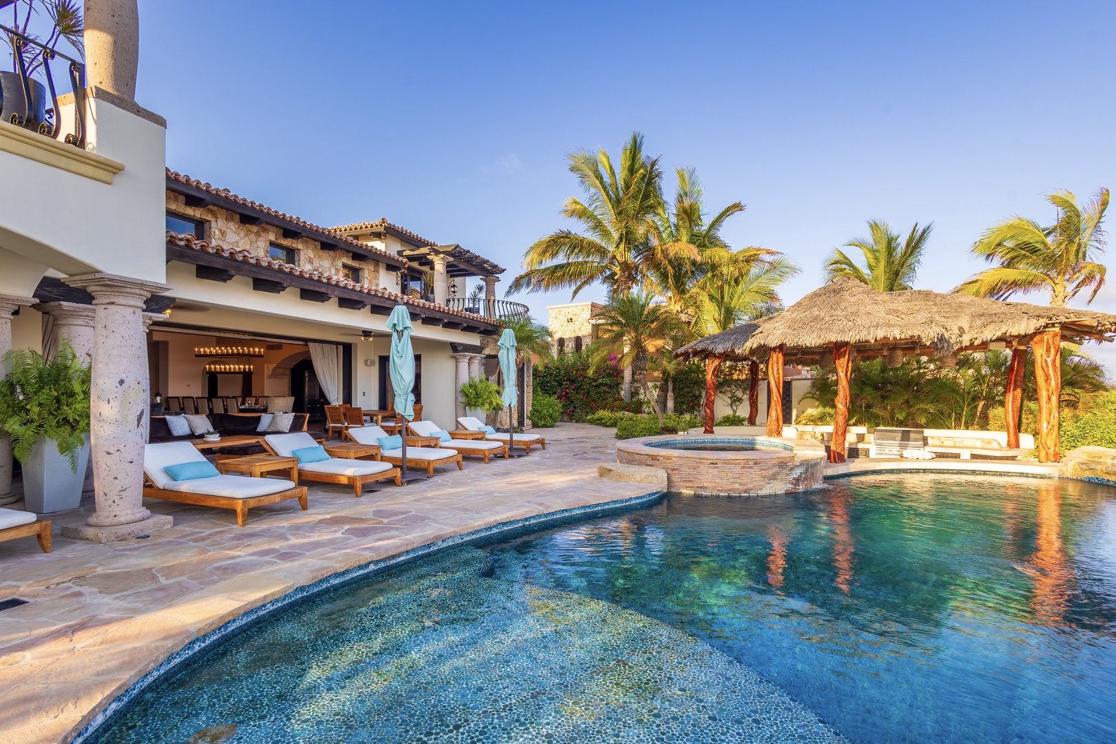 Your private tropical paradise features a sparkling pool framed by swaying palms, thatched palapa, and sunny loungers—perfect for soaking up sunshine and savoring complete relaxation.