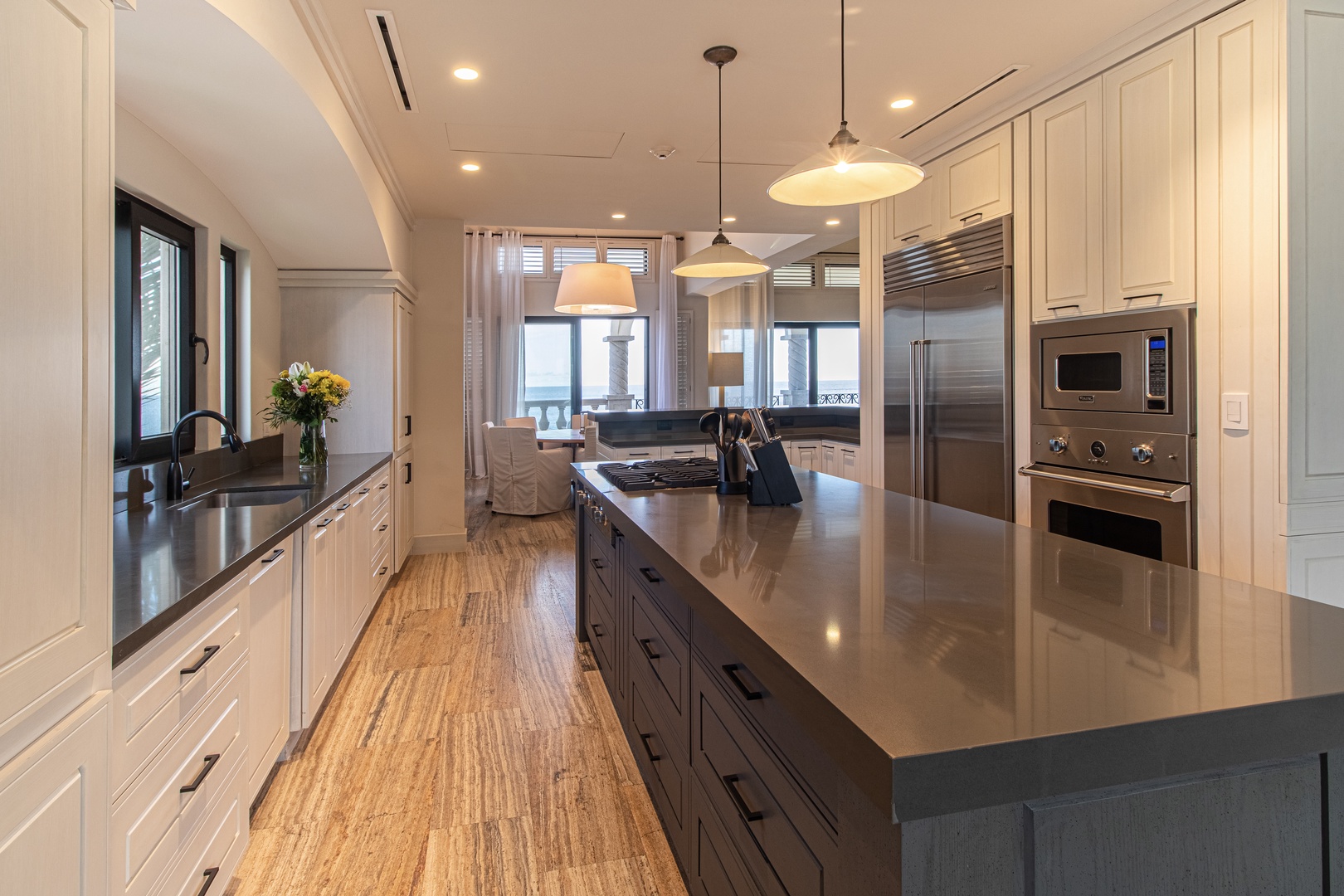 Your fully equipped gourmet kitchen features sleek countertops, modern appliances, and a spacious island—perfect for preparing meals while enjoying stunning ocean views through the windows.