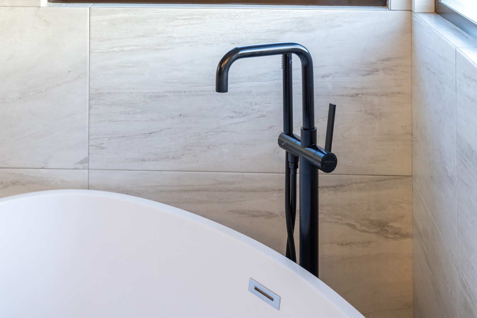 Slip into the sleek freestanding tub after a long day, where elegant matte black fixtures and soft marble-inspired tiles create your own private spa retreat.