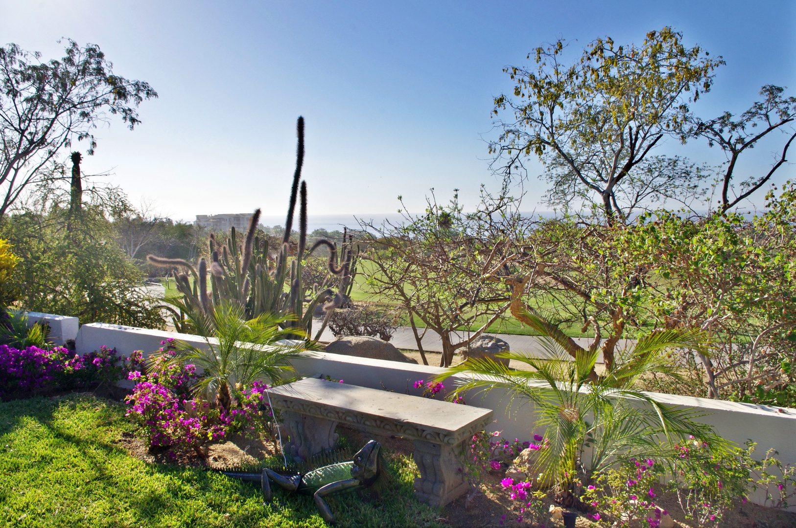 Lush garden with vibrant tropical plantings and natural stone accents overlooks peaceful green fairways beyond the property's low boundary wall.