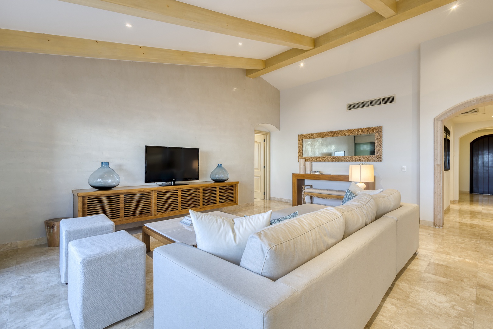 Sink into plush seating in your spacious living area, where exposed wood beams and coastal-inspired décor create a serene retreat for relaxing evenings together.