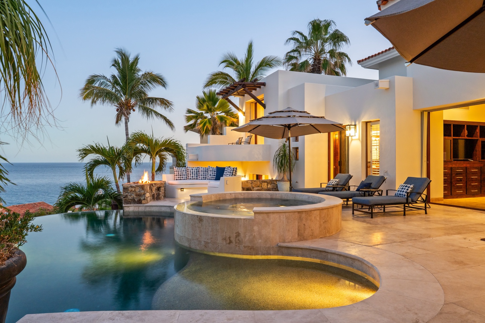 Luxury oceanfront villa with infinity pool, hot tub, and tropical palms creates the perfect sunset retreat.