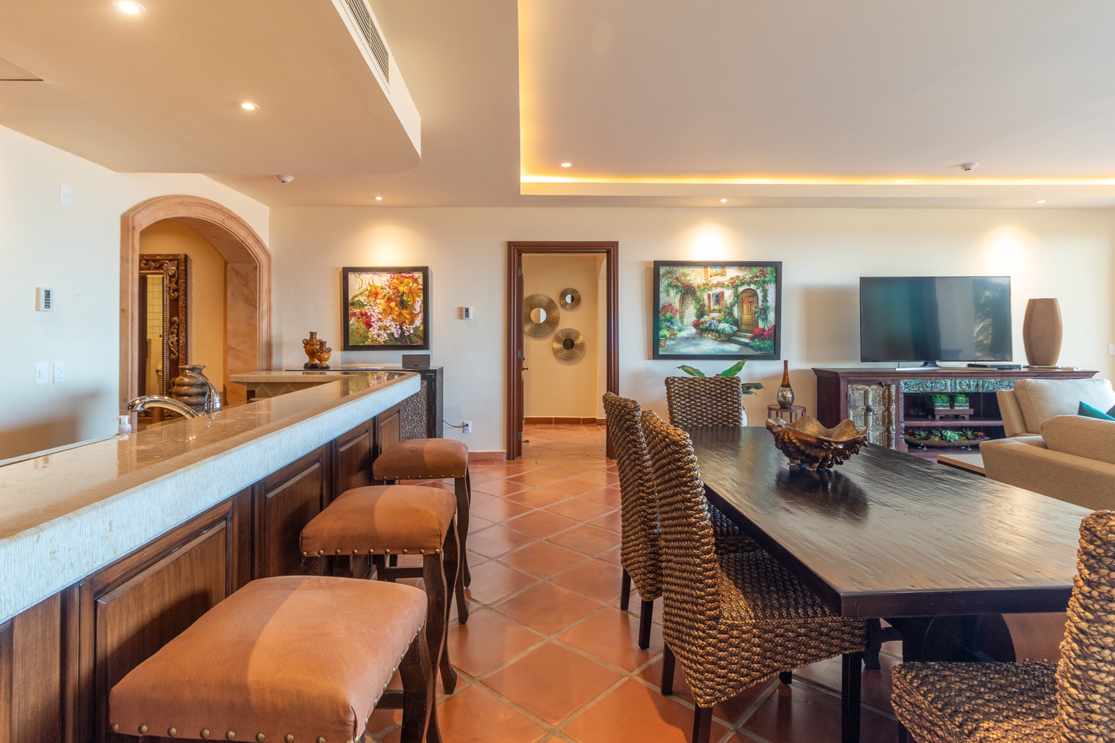 Step into your spacious open-plan living and dining area, where warm terracotta floors and elegant woven seating create an inviting retreat for memorable meals and relaxed evenings together.