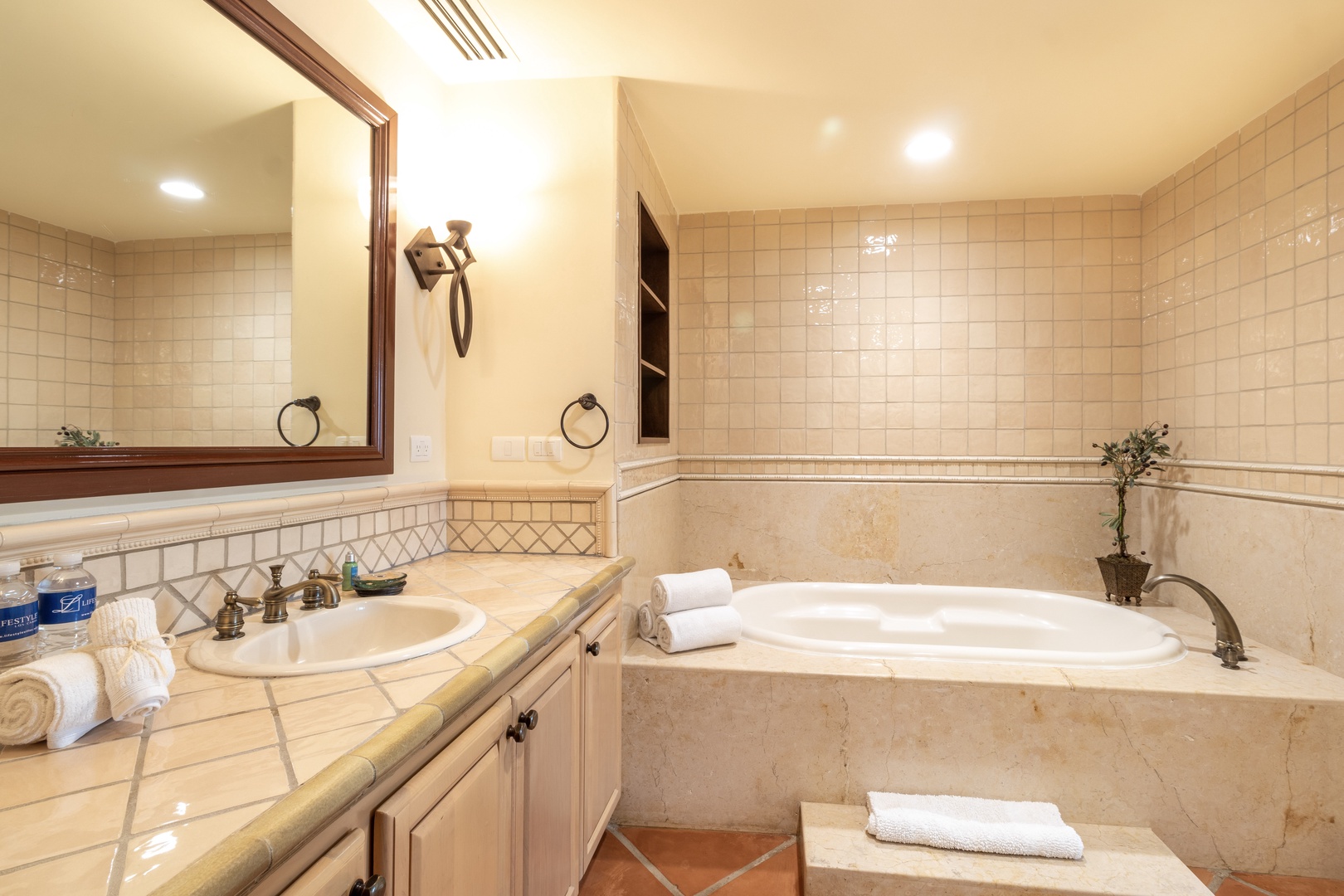 Sink into the warmth of your private bathroom, where creamy tiled walls and a spacious soaking tub invite you to unwind after a day of exploring.