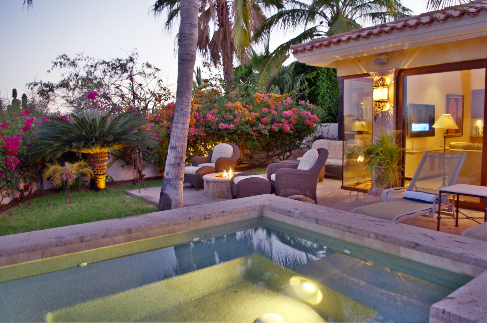 Your private oasis awaits with a glowing pool, cozy patio seating under swaying palms, and lush gardens framing your serene retreat.