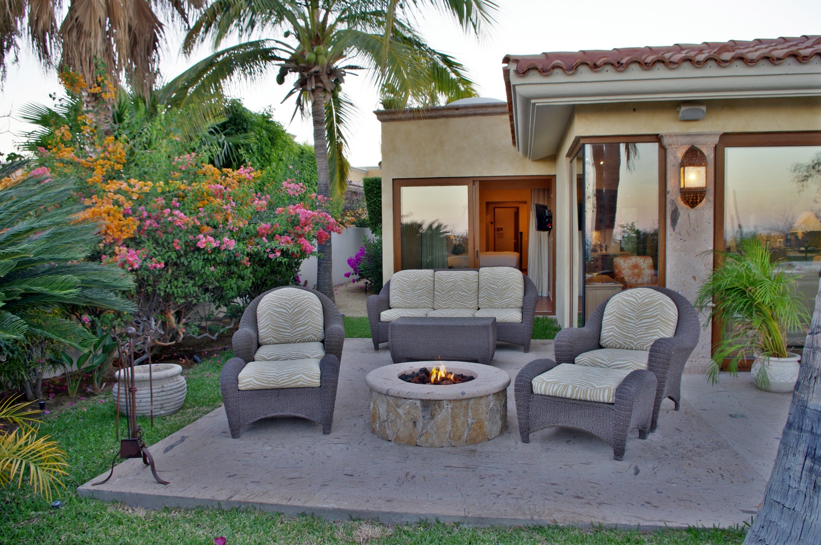 Cozy outdoor patio with fire pit seating surrounded by tropical landscaping and direct access to your vacation retreat.