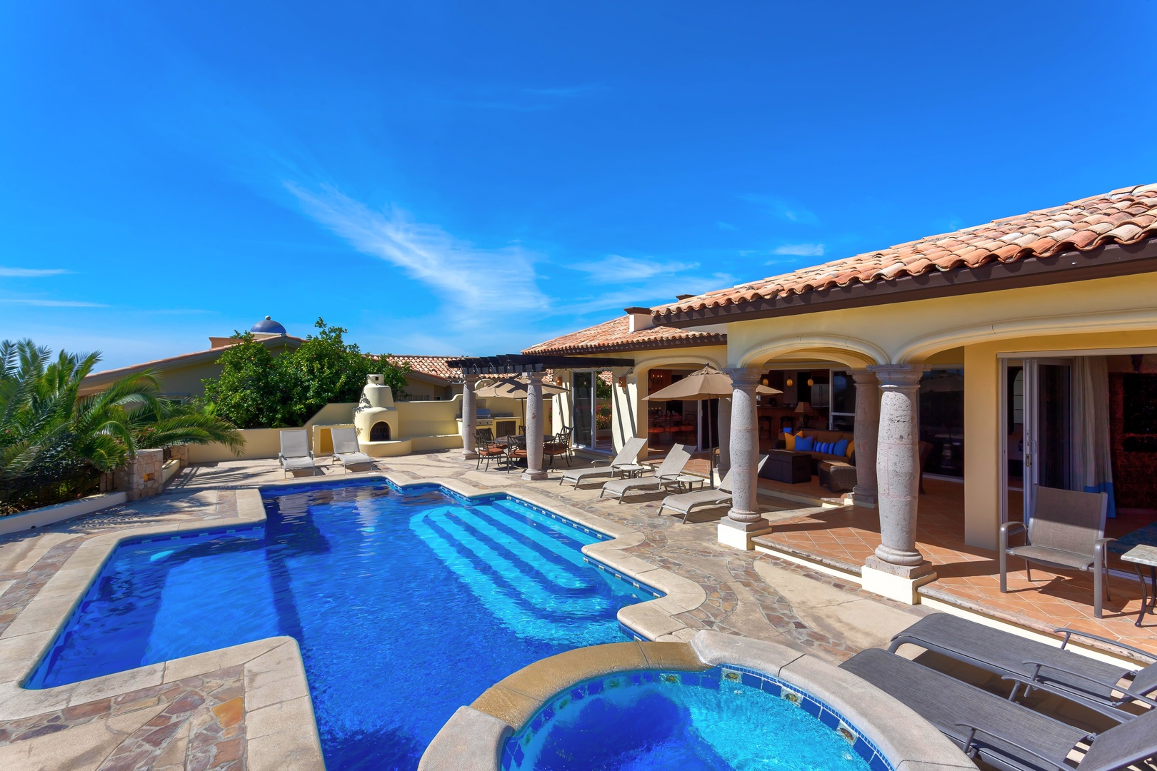 Stunning villa with private pool and spa under brilliant blue skies, surrounded by lush tropical landscaping.