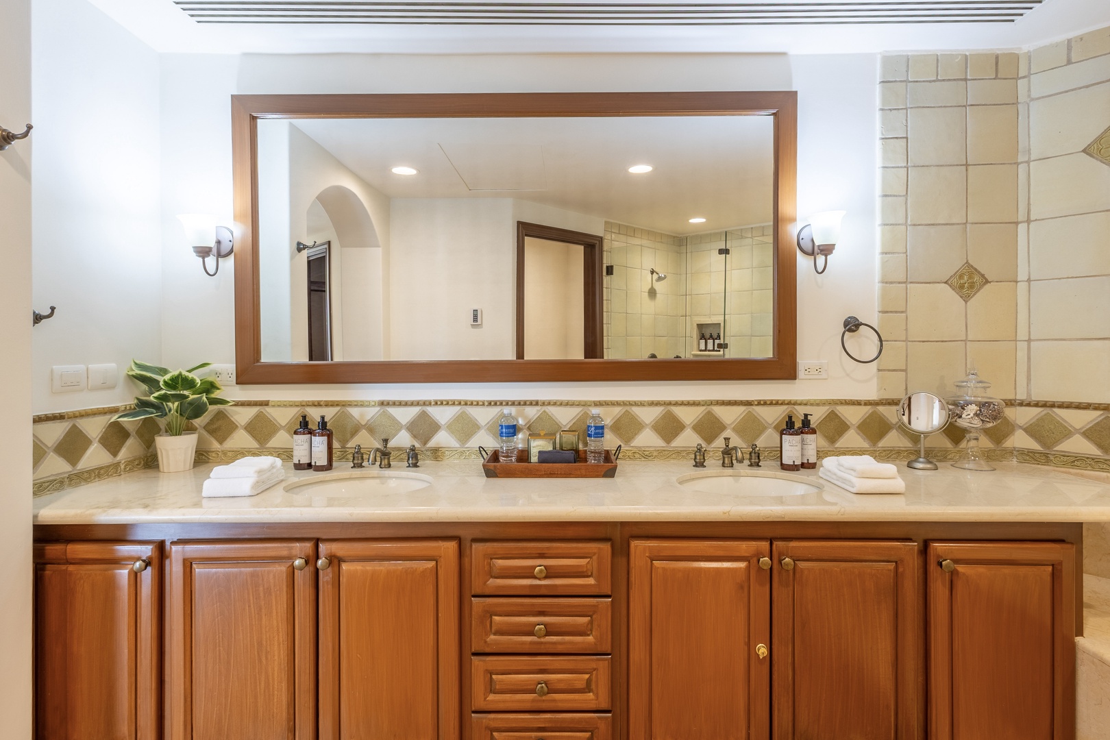 Indulge in your spacious marble bathroom with dual sinks, elegant wood cabinetry, and luxurious amenities for a spa-like experience.