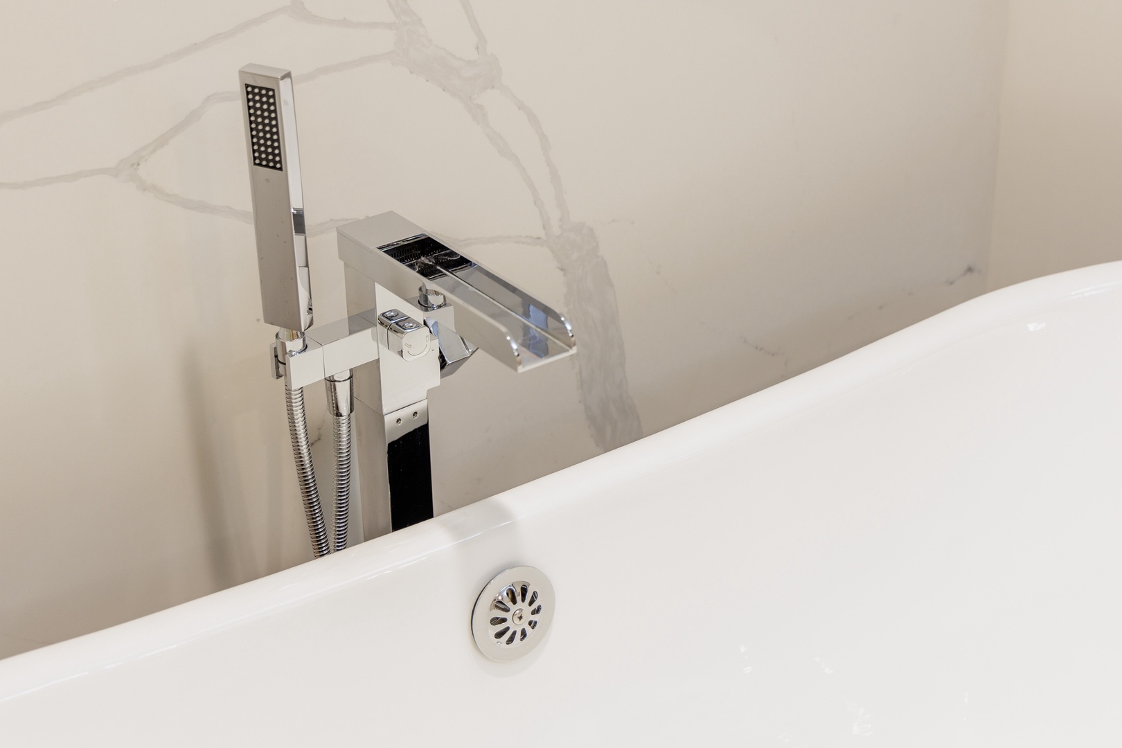 Slip into this deep modern tub with a sleek waterfall faucet and rainfall shower attachment—your private spa awaits after exploring.