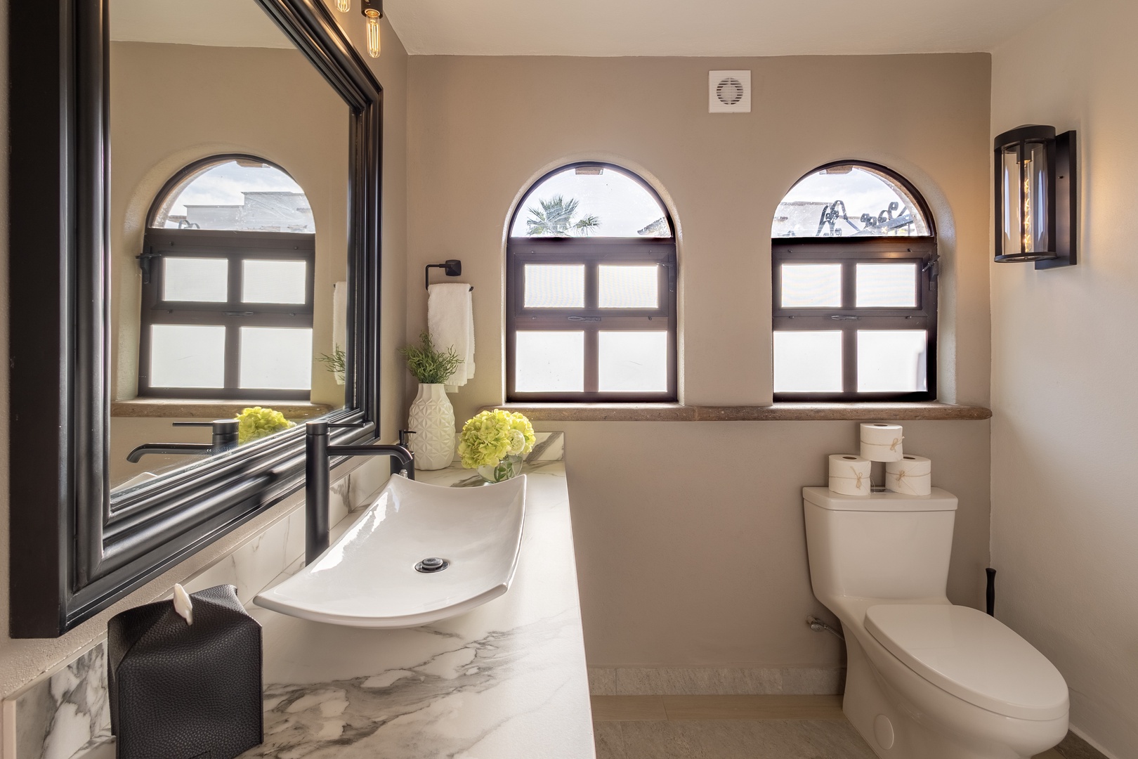 Step into your private sanctuary where elegant arched windows frame serene palm views, and a sculptural vessel sink adds artistic charm. Fresh towels and blooms await your arrival, making every moment feel like a spa retreat.
