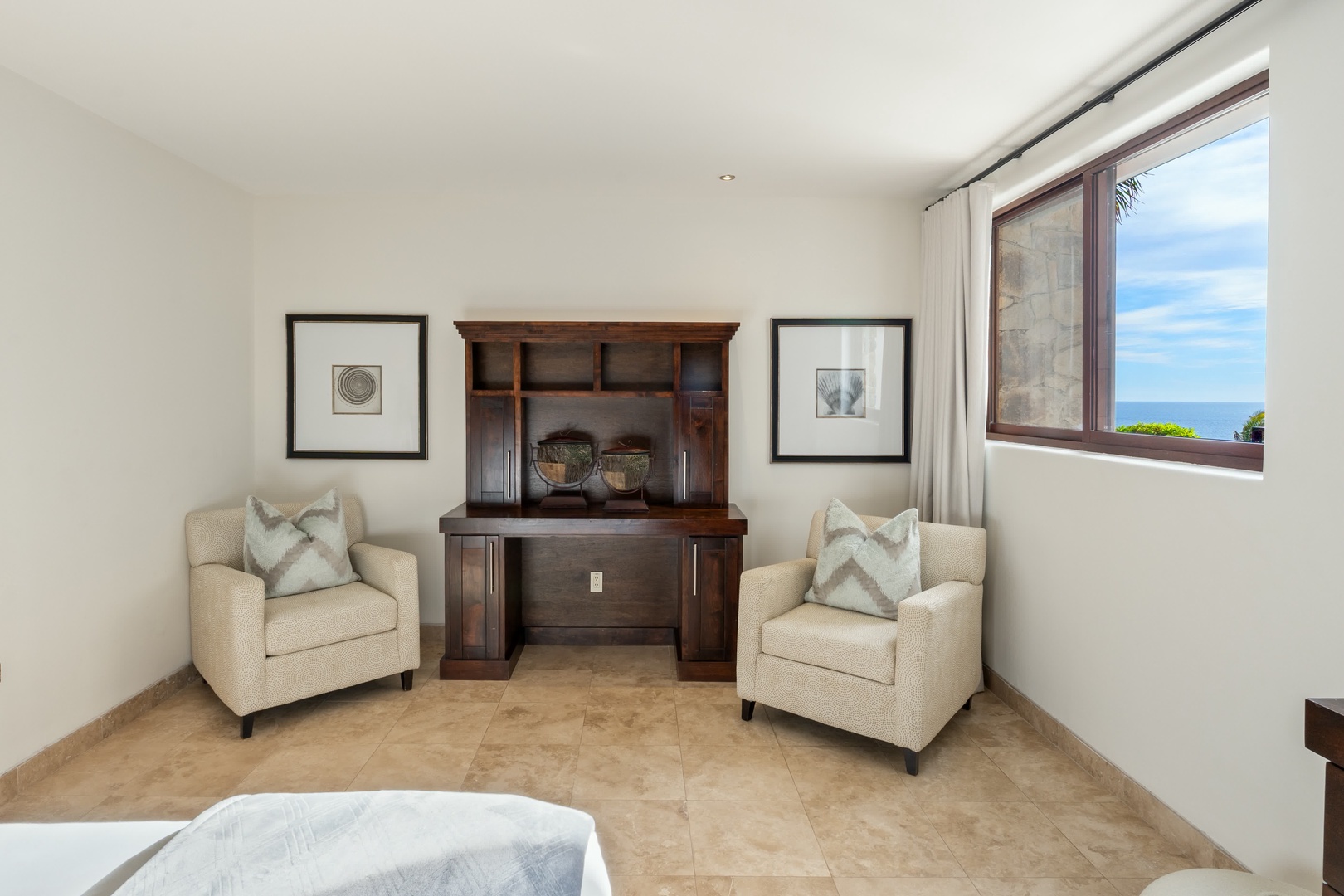 Relax in your elegant seating area with comfortable armchairs and ocean views through the large window.