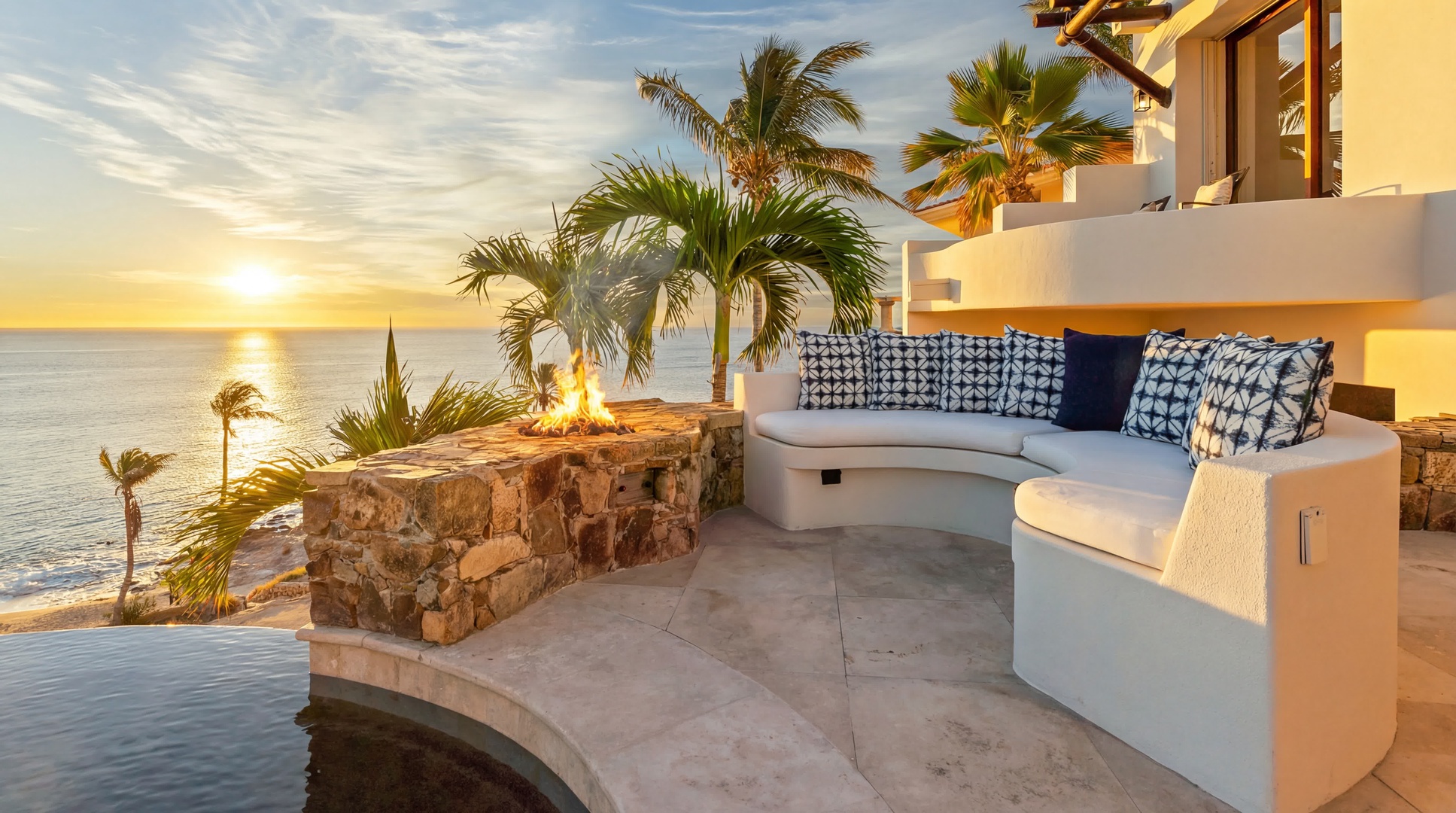 Unwind on your private terrace with ocean views, cozy seating, and fire feature as golden sunsets paint the sky.
