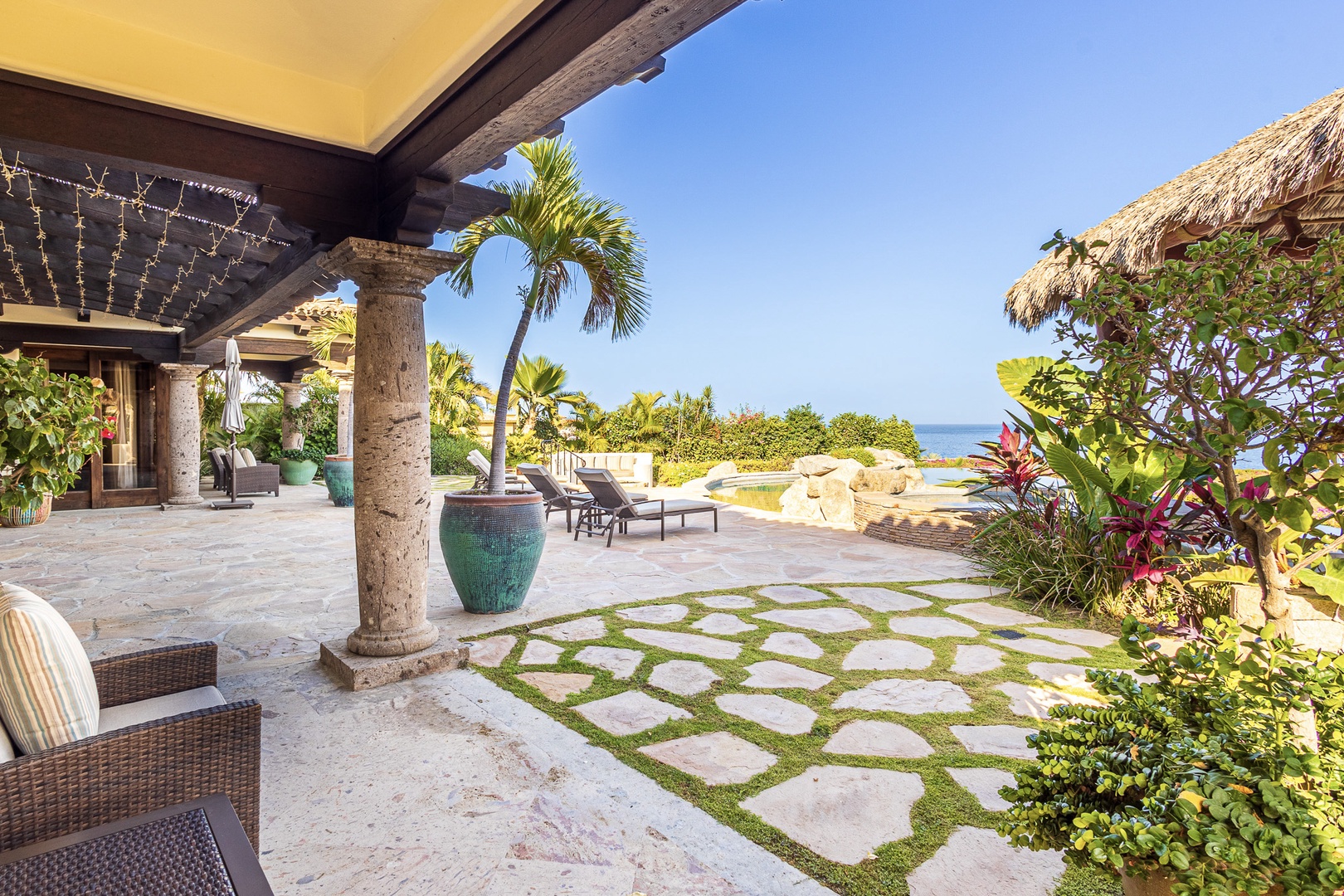 Stunning oceanfront villa features a covered terrace, tropical landscaping, and private pool overlooking the sea—an idyllic beachside paradise setting.