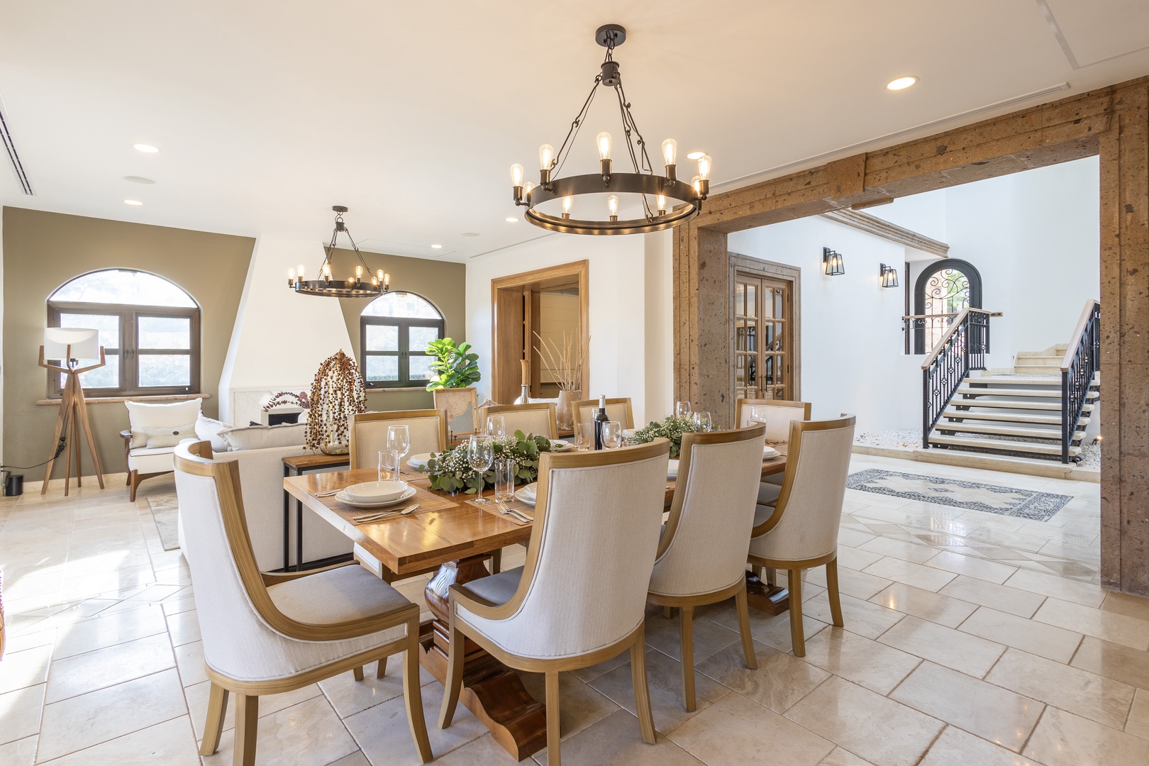 Gather around this elegant dining table for memorable meals beneath warm chandelier light, with views spilling into inviting living spaces beyond.