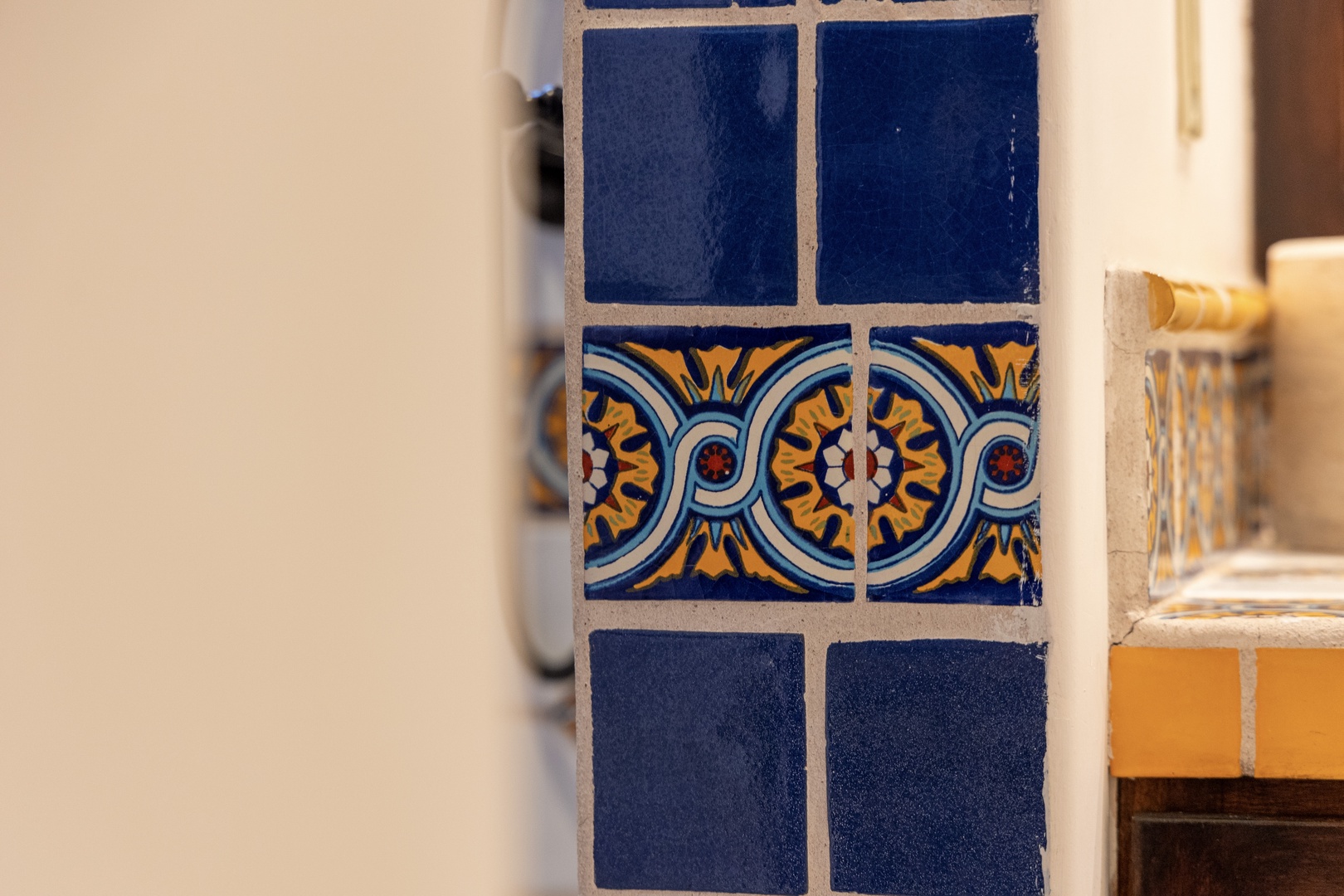 Vibrant hand-painted tiles bring authentic character and artisan charm to your space, featuring rich Mediterranean blues and golden yellows in a traditional floral pattern.