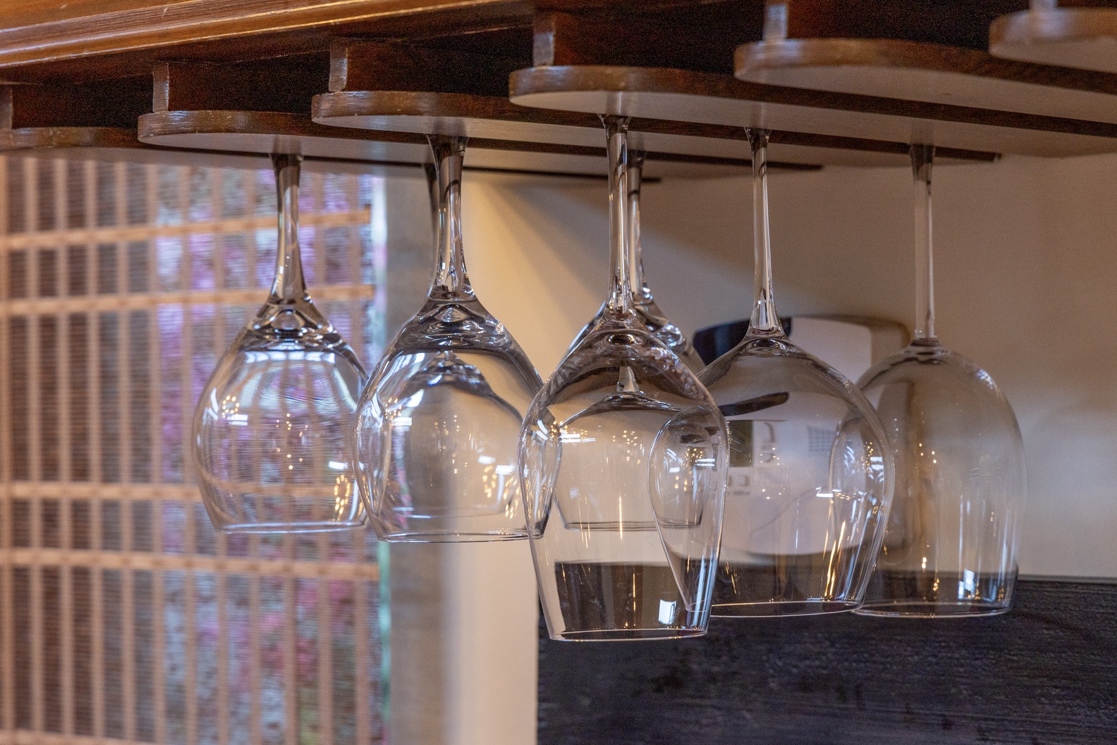 Your glasses hang ready in this thoughtfully designed bar area, where polished stemware gleams beneath warm wood shelving—perfect for unwinding with evening drinks.