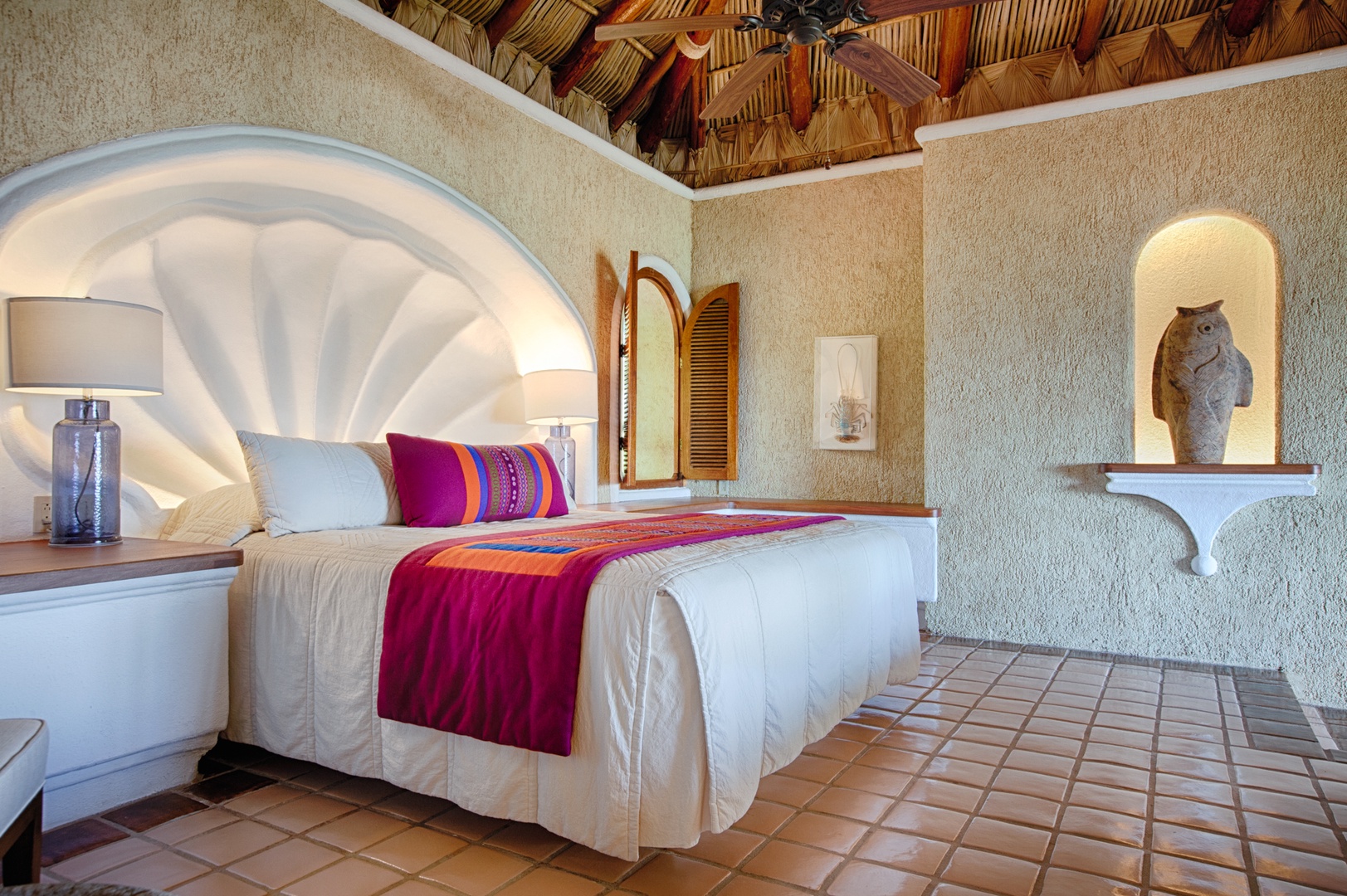 Your serene bedroom features traditional architecture with a striking arched headboard, colorful textiles, and authentic Mexican décor creating a peaceful retreat.