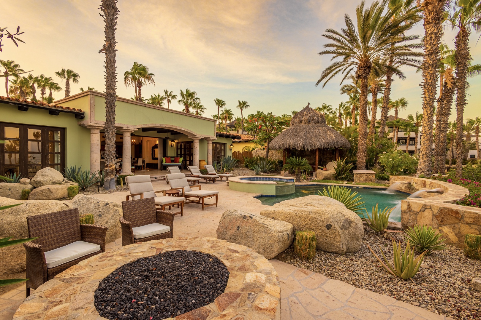 A private desert oasis awaits with your own pool, thatched palapa, and loungers nestled among palm trees and natural boulders. Unwind poolside in tropical serenity.