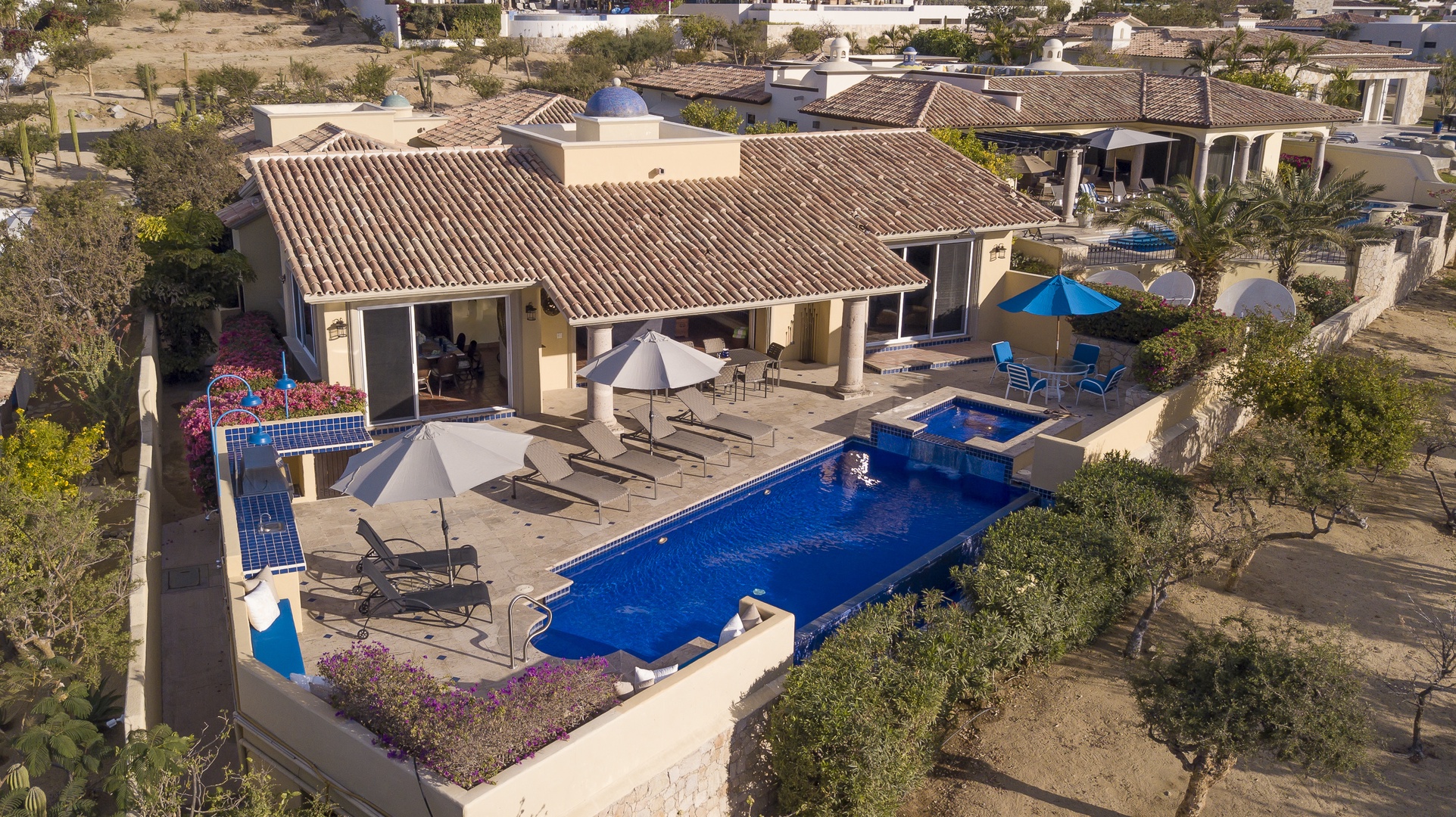 Aerial view of this stunning villa showcasing the expansive pool area and Mediterranean-style architecture in a peaceful residential setting.