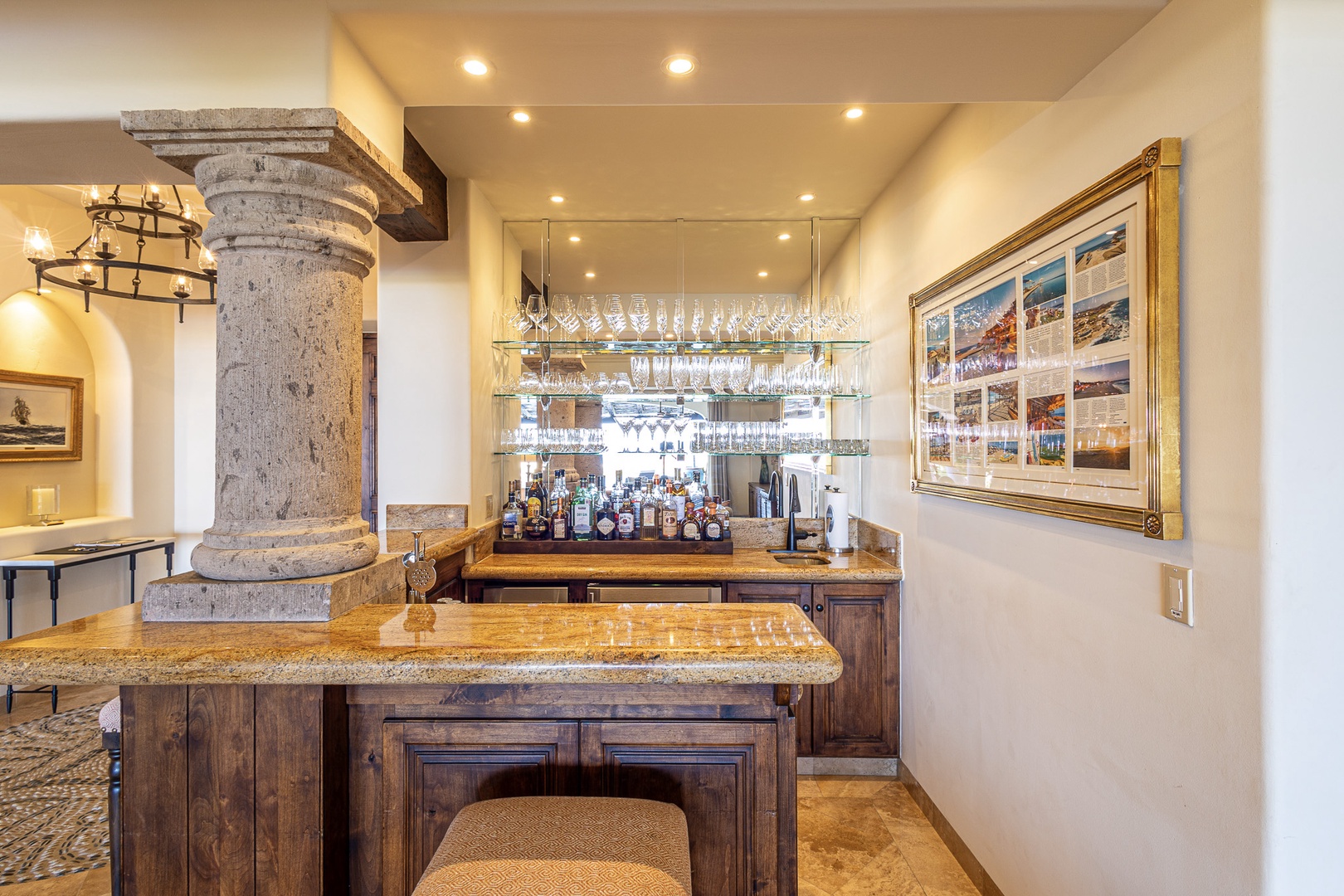 You'll love the custom-built bar with its granite countertop, elegant glassware display, and rustic stone column detail—perfect for mixing your favorite cocktails and entertaining in style.