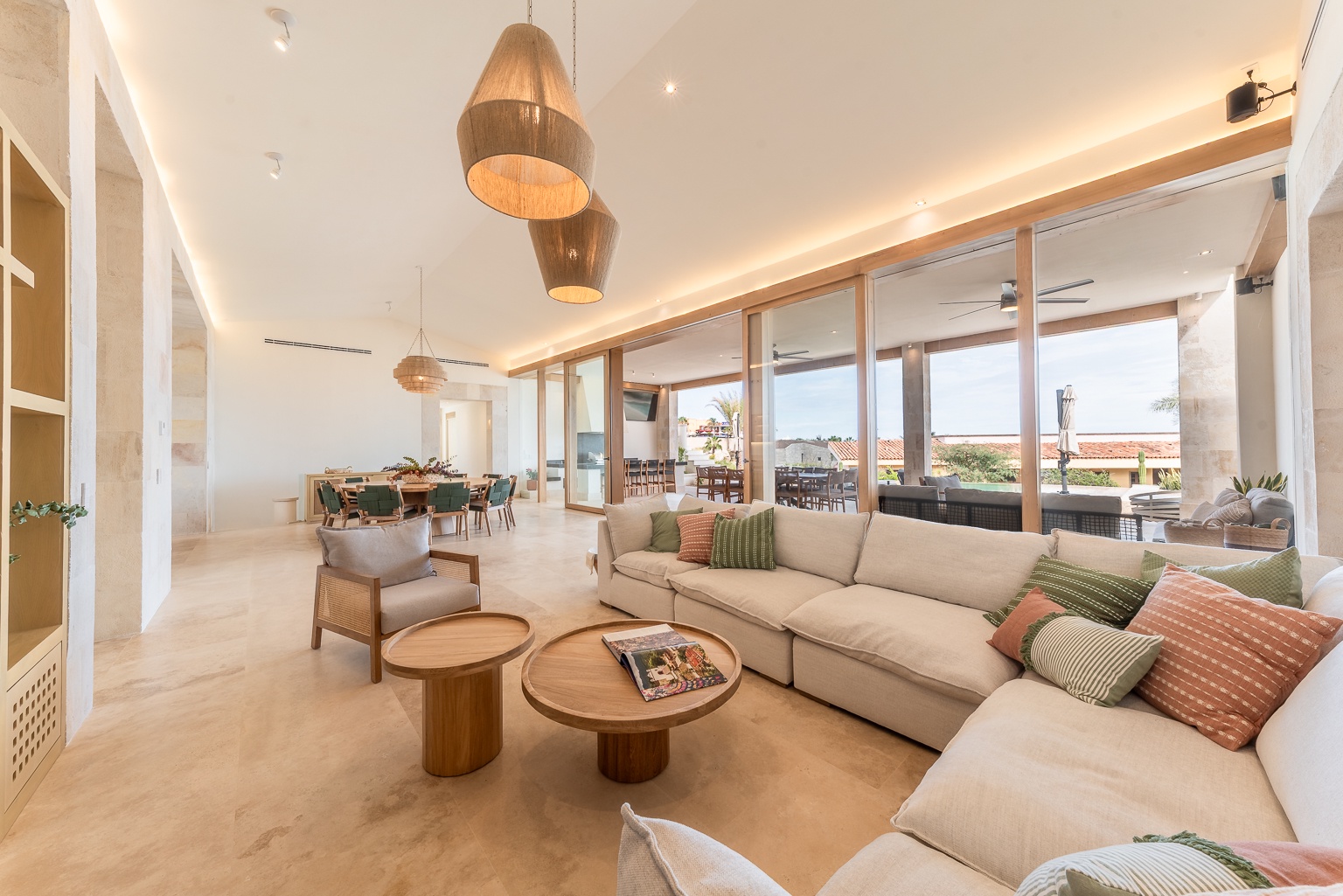 Picture yourself unwinding on plush sofas beneath warm pendant lights as tropical breezes flow through open terrace doors, framing distant palm trees and terra-cotta roofs.
