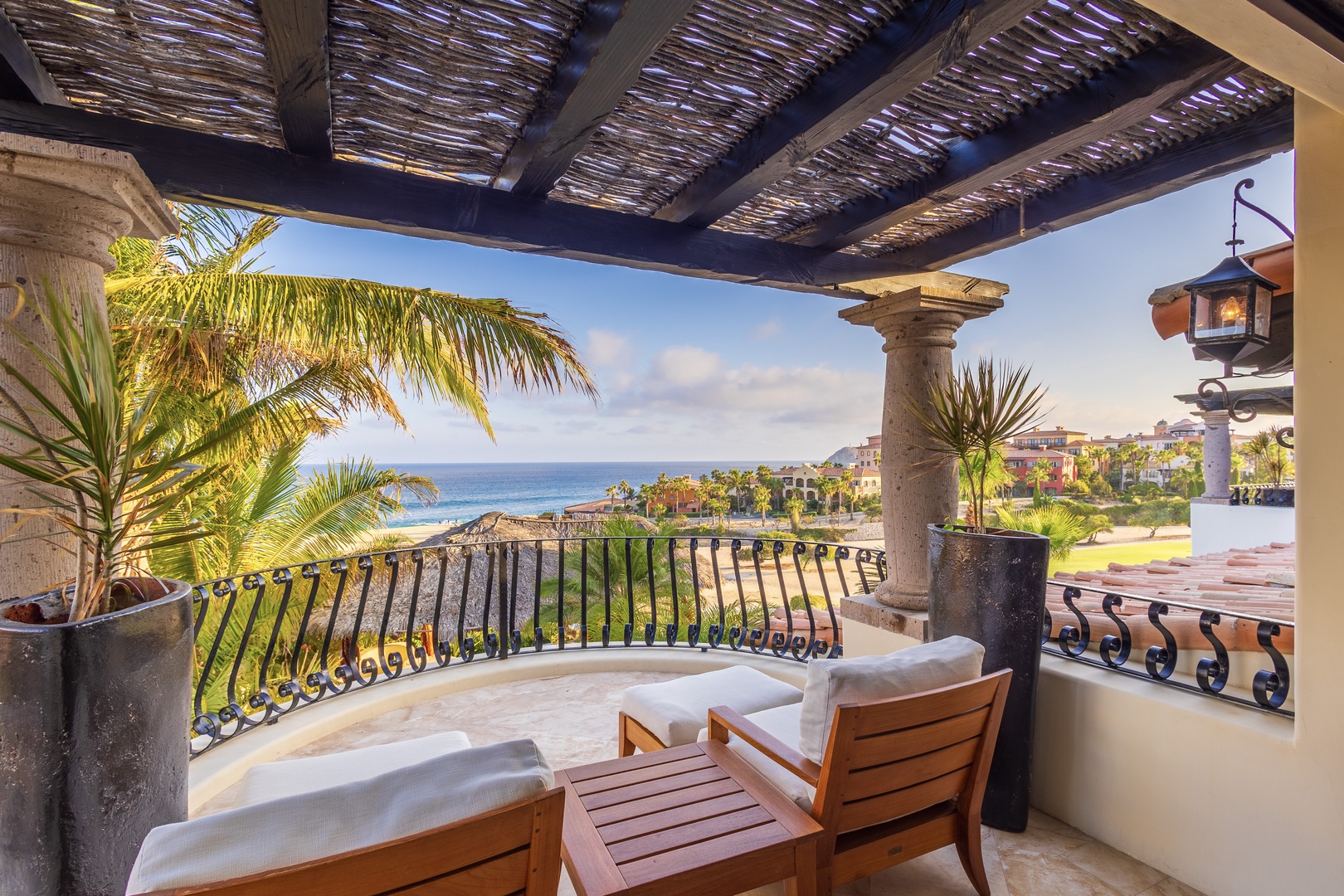 Relax on your private terrace with stunning ocean and coastal views. Comfortable seating, tropical plants, and warm lighting create your perfect escape under a charming pergola.