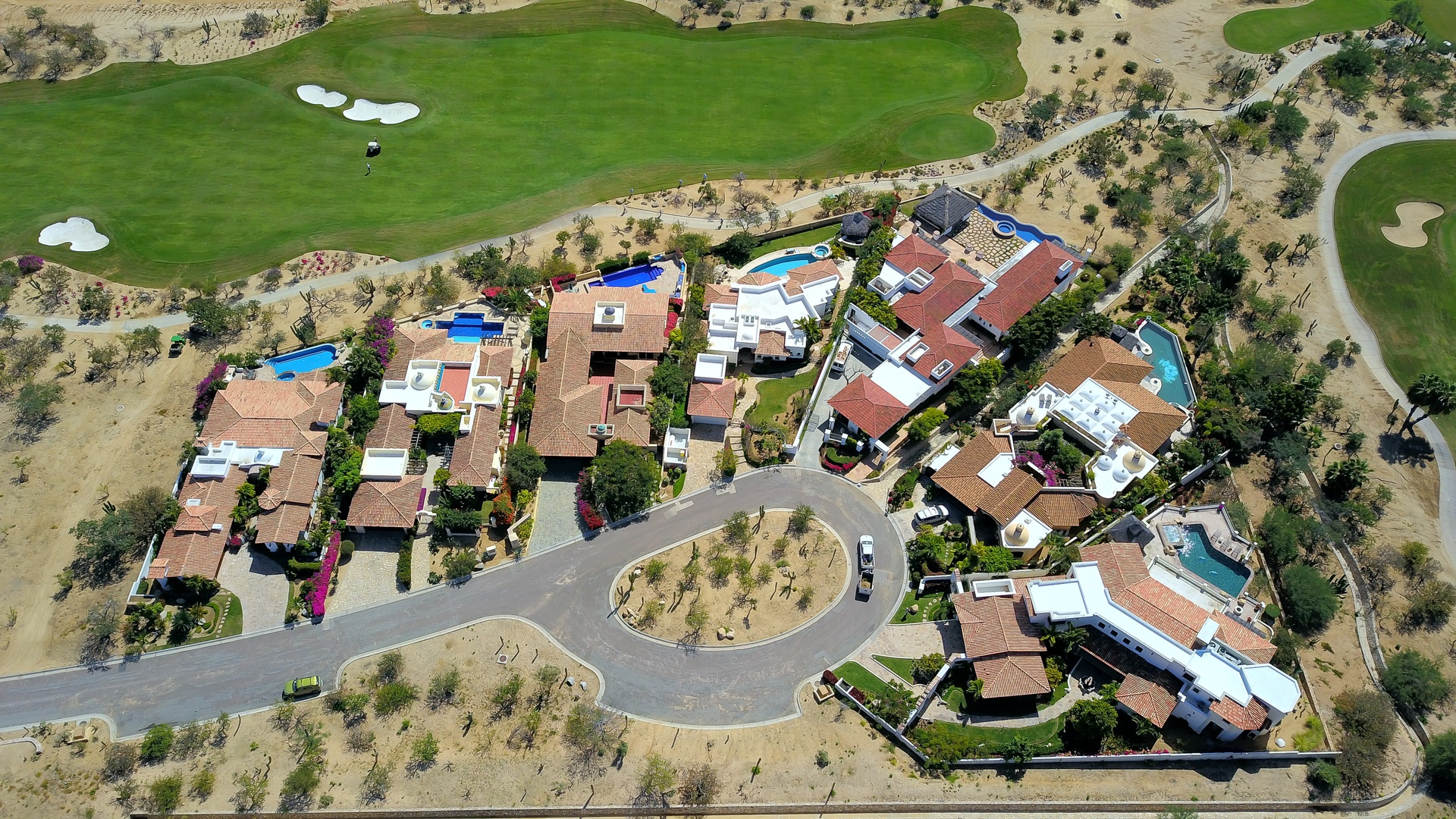 Aerial view of an exclusive residential community adjacent to pristine golf course fairways and sand bunkers.