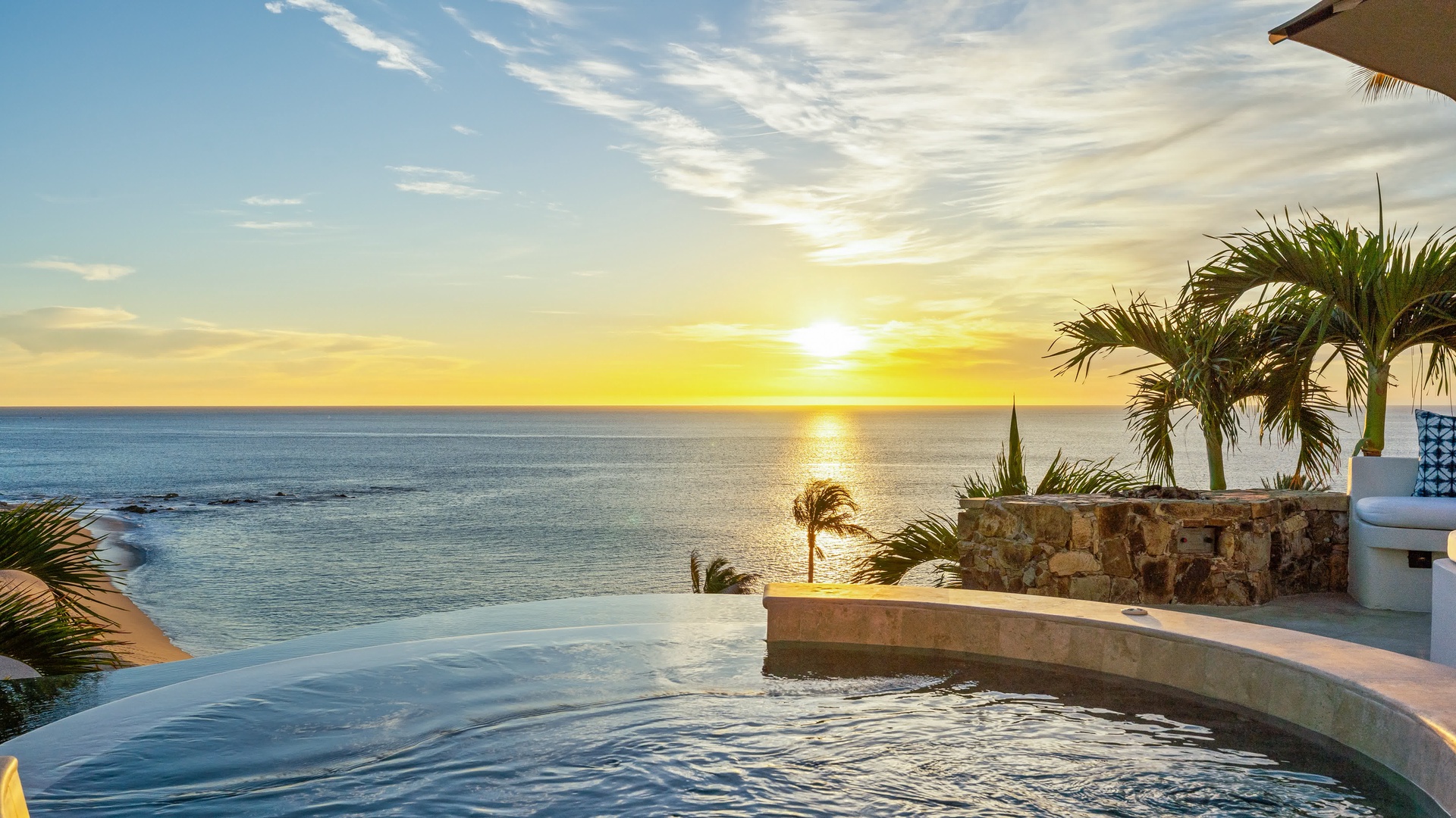 Stunning oceanfront infinity pool with golden sunset views over endless blue waters and swaying palm trees.