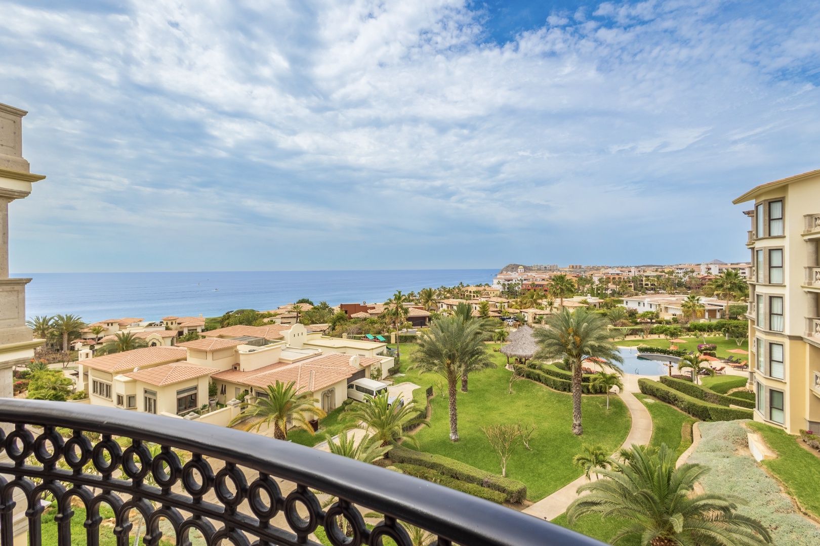 Sweeping ocean views stretch across lush resort grounds with palm trees and pools from your private balcony.
