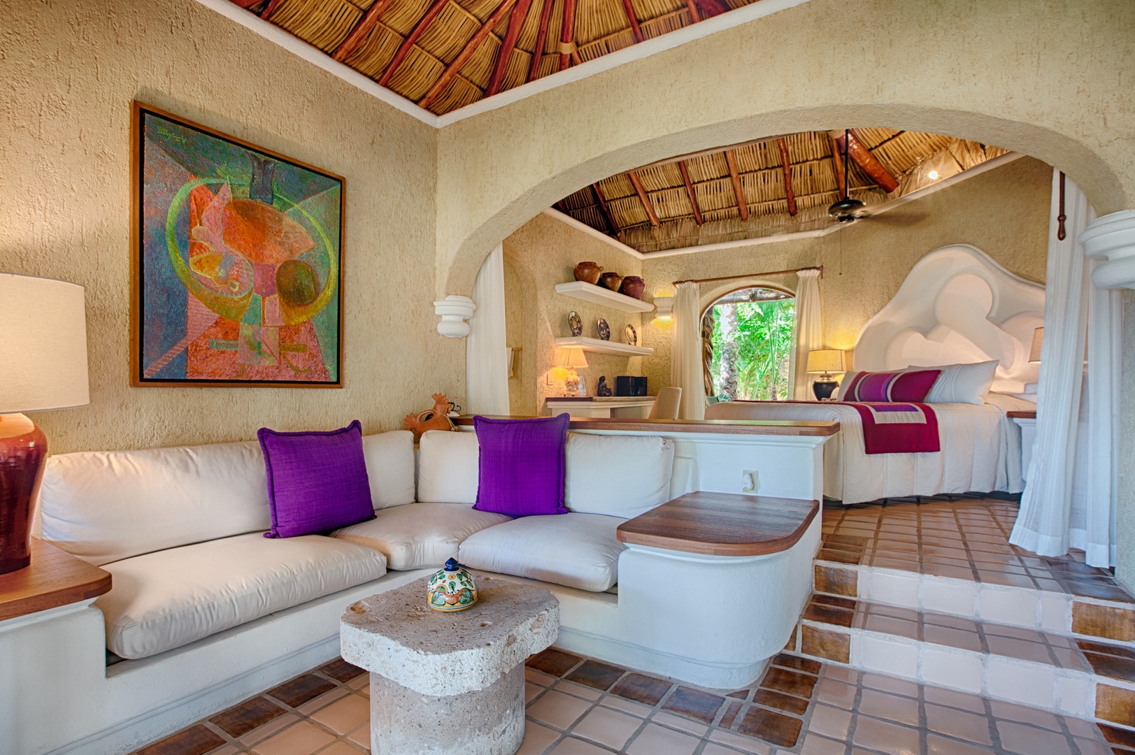 Discover your enchanting sanctuary with soaring palapa ceilings, vibrant artwork, and plush seating leading to your dreamy bedroom retreat.