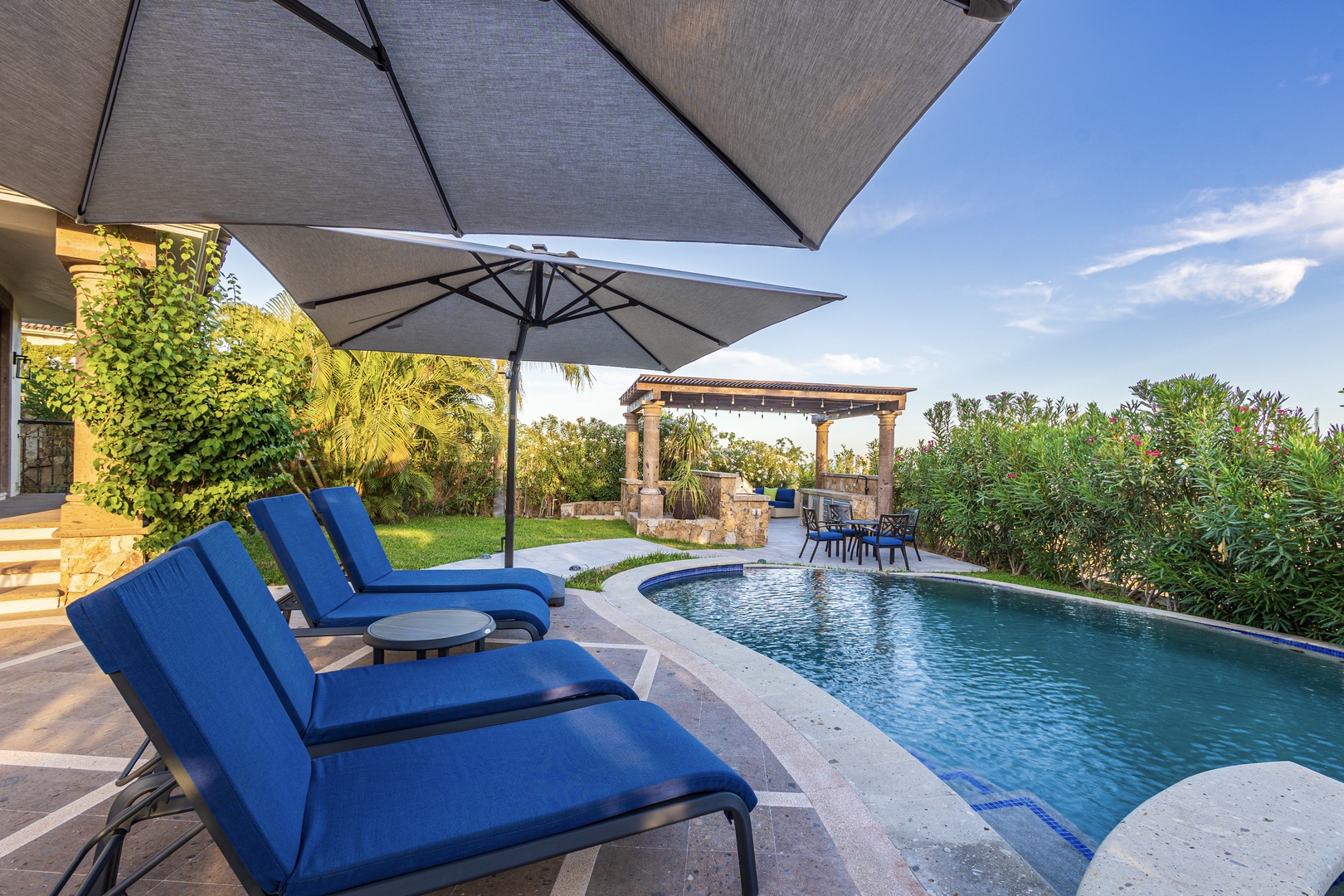Stretch out on plush poolside loungers under your private umbrella, gazing at lush gardens and the sparkling pool inviting you to relax under clear skies.