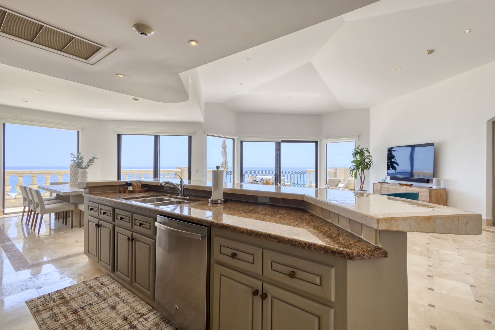 Sunlight floods your open-concept kitchen and dining space, where stunning sea views stretch beyond expansive windows and your private balcony invites serene coastal moments.