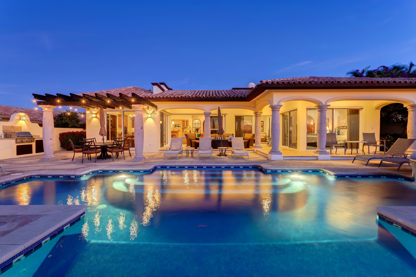 Elegant Mediterranean villa with illuminated swimming pool creates a stunning evening atmosphere for luxurious relaxation and entertainment.