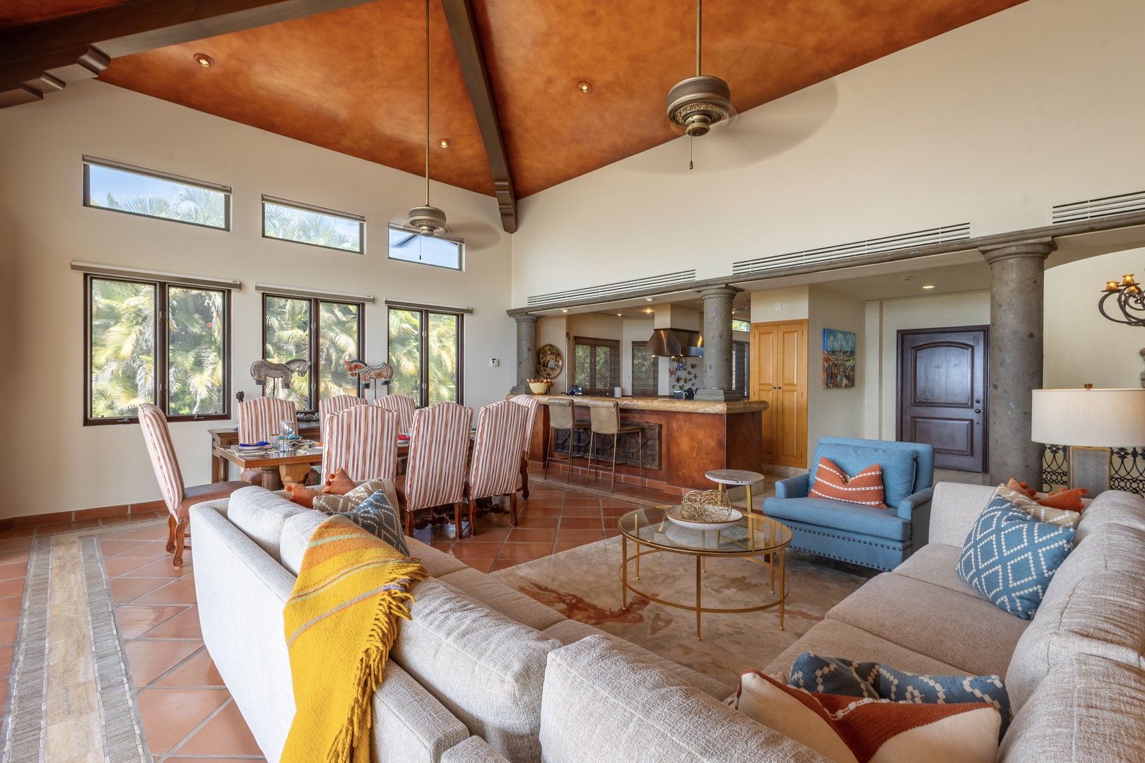 Relax in your spacious living and dining area featuring vaulted wood ceilings, abundant natural light, and an open layout flowing seamlessly into the fully equipped kitchen—perfect for gathering and unwinding.