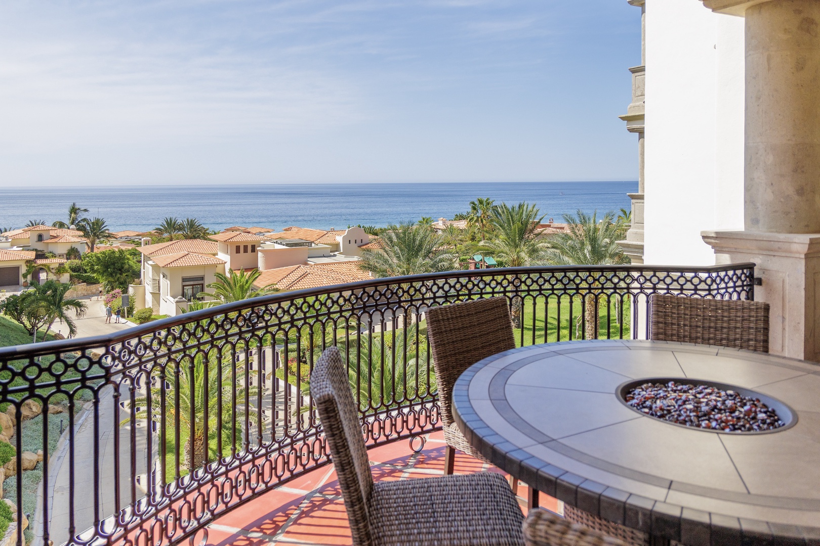 Settle into your private terrace with wicker seating and an inviting fire pit as you take in stunning sea views stretching across Mediterranean-style rooftops and swaying palms.
