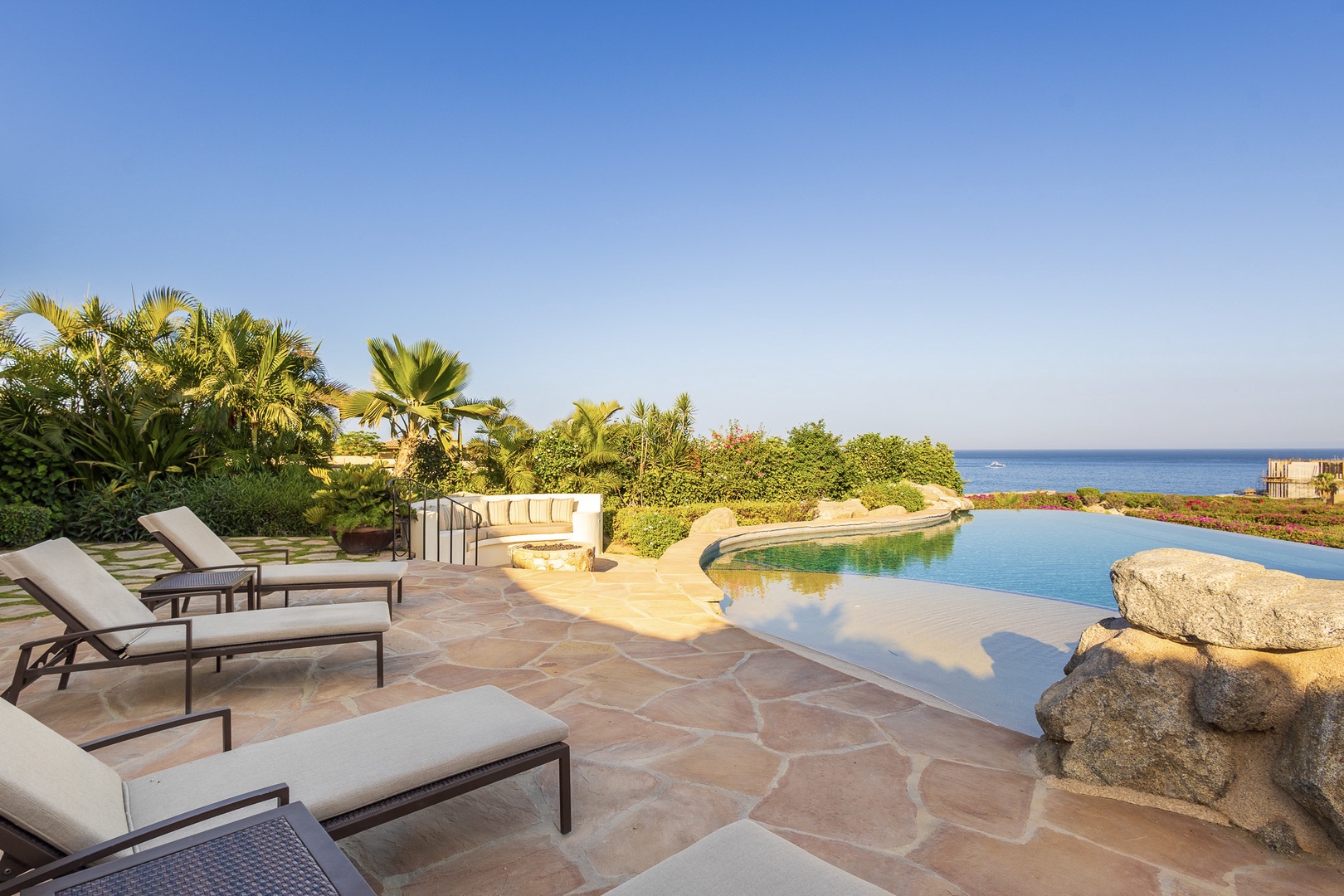 A stunning infinity pool overlooking the sea awaits, surrounded by tropical palms and plush loungers for your perfect seaside retreat.