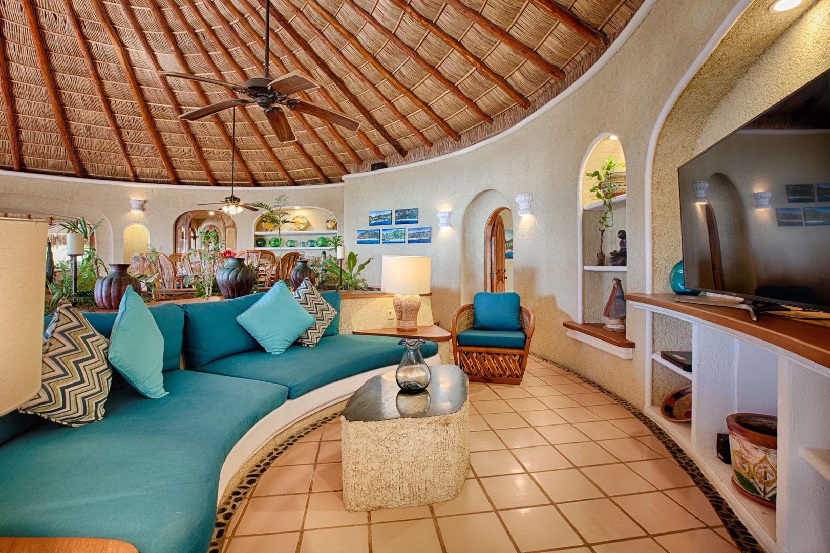 Relax in your spacious living room with vibrant turquoise seating and stunning palapa ceiling, creating a perfect tropical sanctuary.