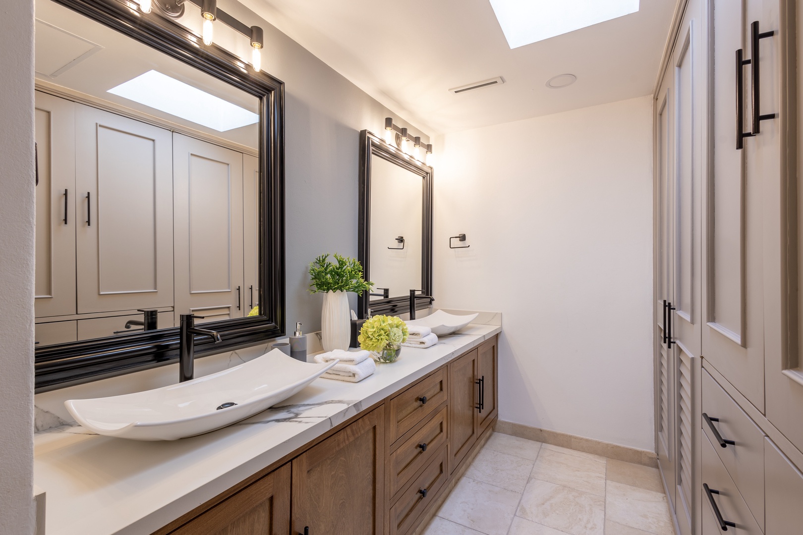 Refresh in your spa-inspired bathroom, complete with dual vanities, chic framing, and crisp white towels ready for you. Natural light pours through the skylight above.
