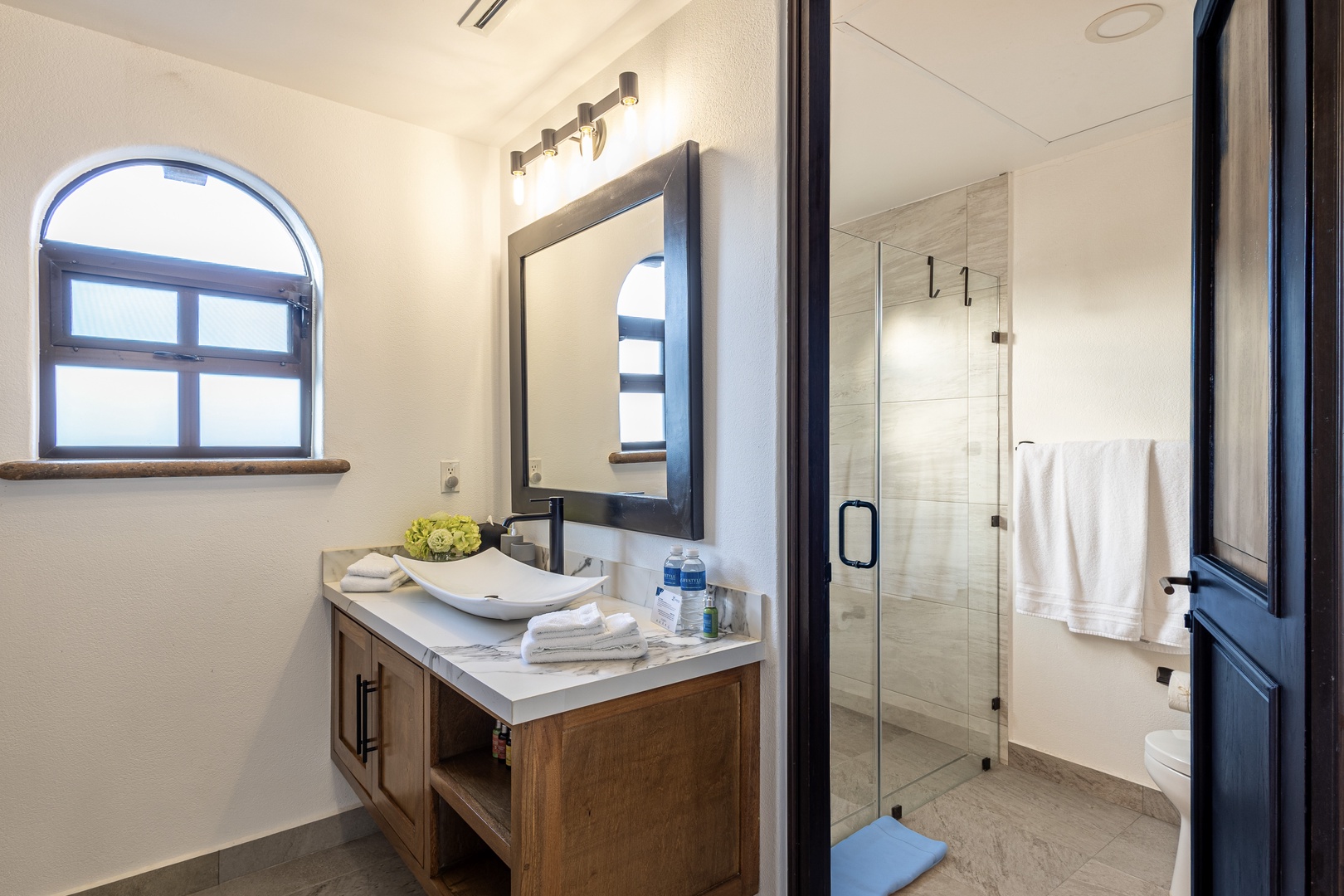 Step into your beautifully appointed bathroom with a spacious walk-in shower, stylish vessel sink, and fresh towels awaiting your arrival. Natural light and modern finishes create a serene space to unwind.