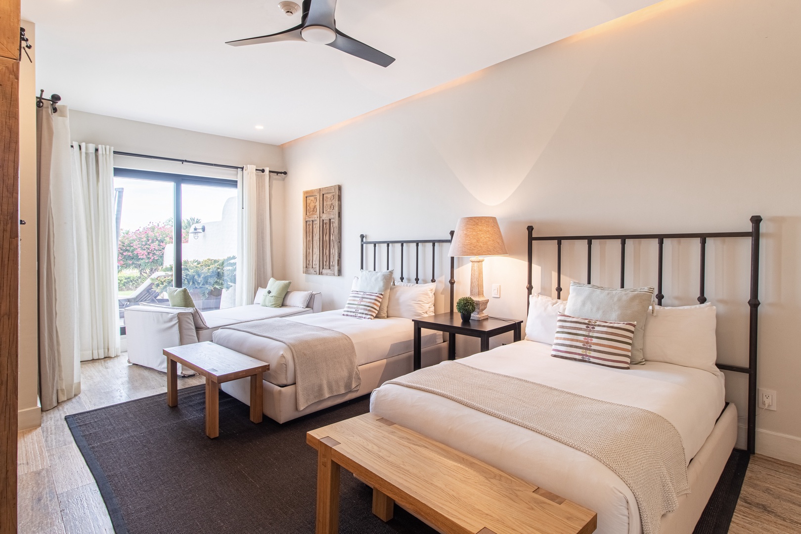 Sink into plush beds with crisp linens and decorative pillows. You'll drift off under the ceiling fan's gentle breeze, while natural light pours through curtained windows, creating your perfect retreat.