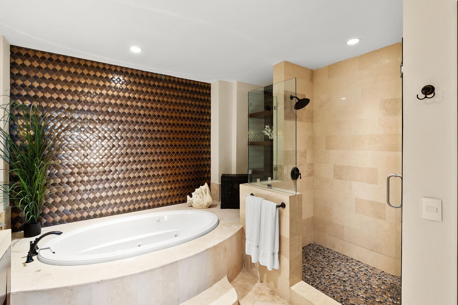 Indulge in your private spa retreat with a deep soaking tub and spacious walk-in shower, framed by striking textured walls and calming neutral tones that invite you to unwind completely.