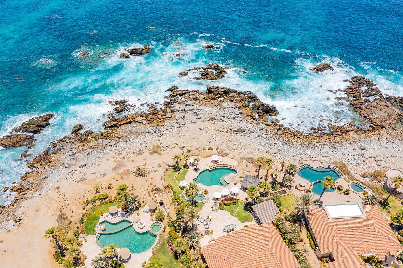 Spectacular oceanfront resort with multiple pools set against dramatic rocky coastline and crystal-clear turquoise waters.
