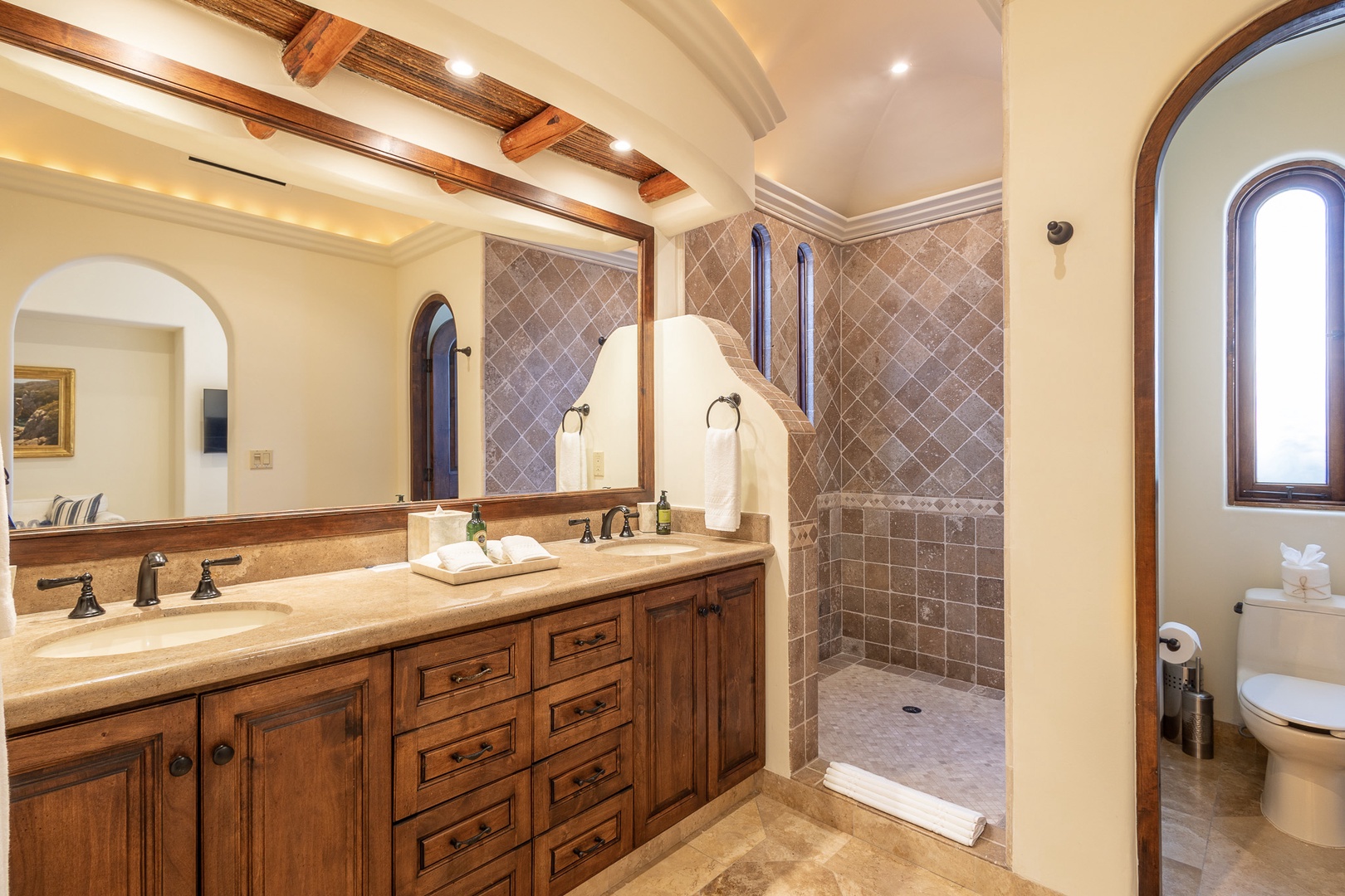 Step into your private spa-like retreat with a spacious walk-in shower, elegant travertine tile, and warm wood details throughout. The double vanity offers ample space to settle in and unwind.