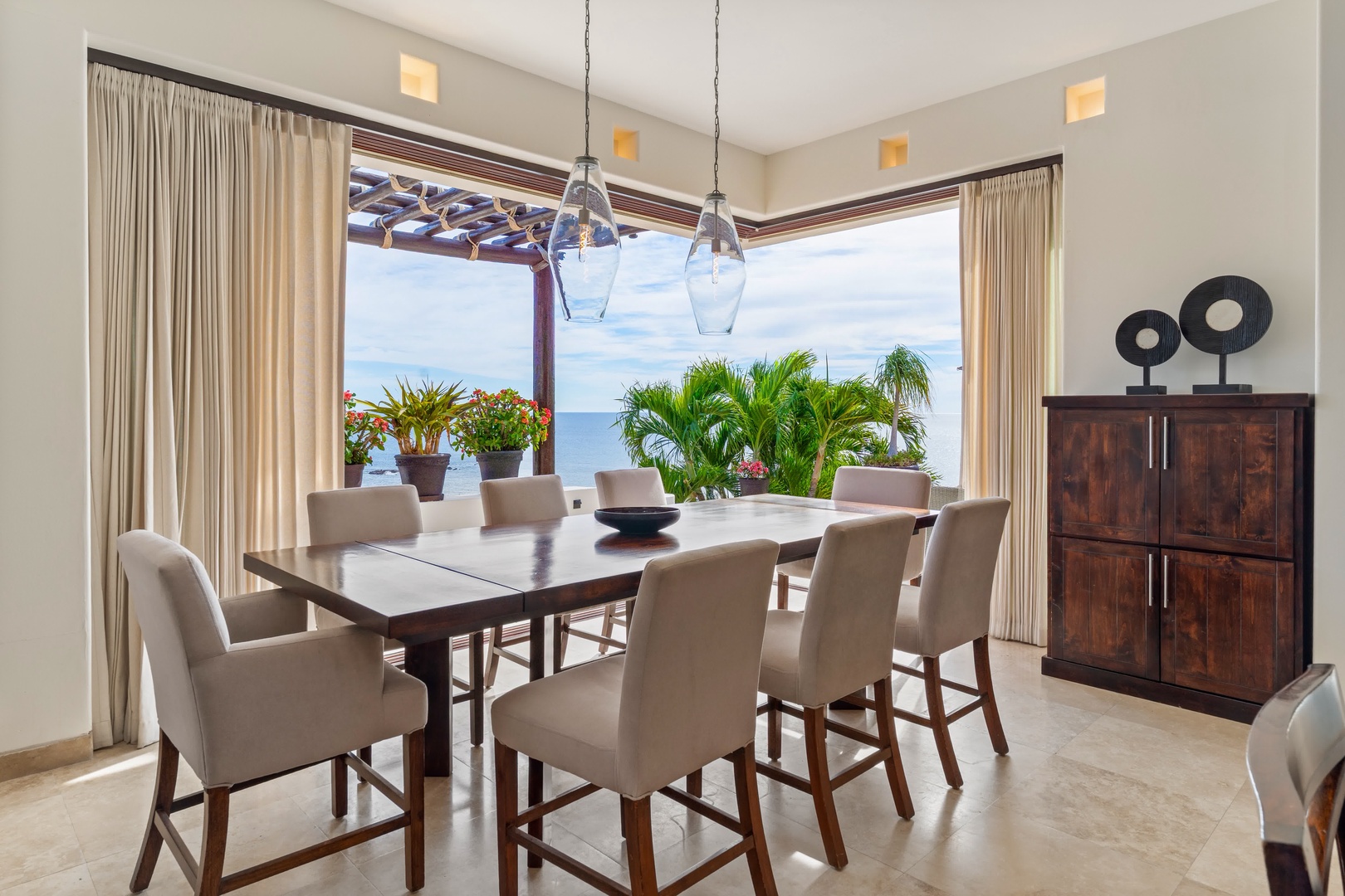 Savor memorable meals at your elegant dining table with breathtaking ocean views through expansive windows.