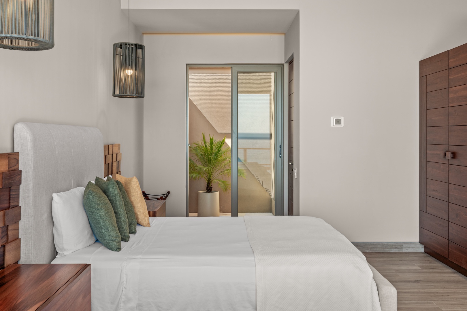 Sink into crisp linens and unwind in your serene bedroom, where modern design meets coastal comfort. Step through sliding doors to your private outdoor retreat just beyond.