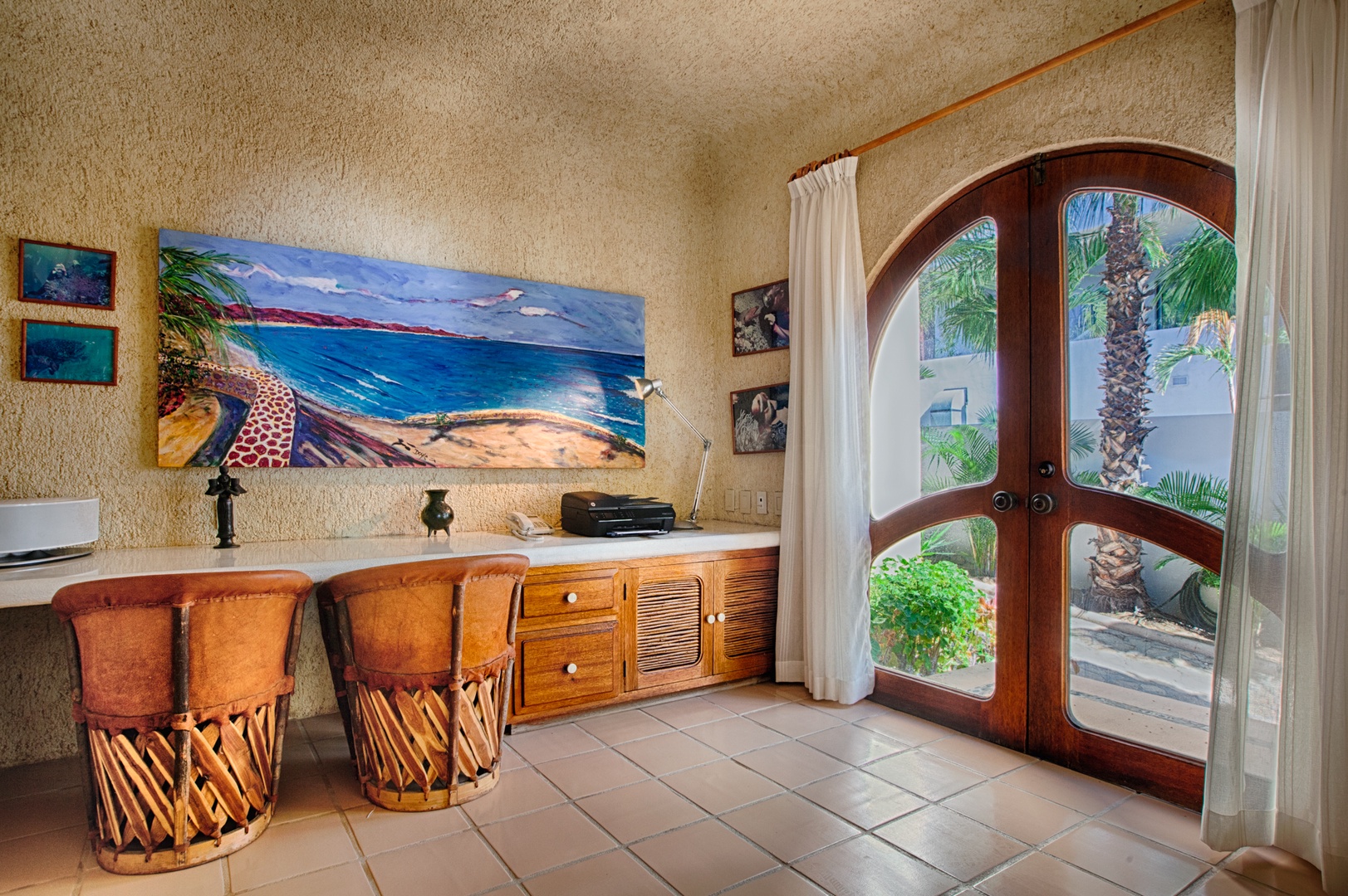 Settle into your cozy workspace with tropical artwork and arched doors opening to lush garden views.
